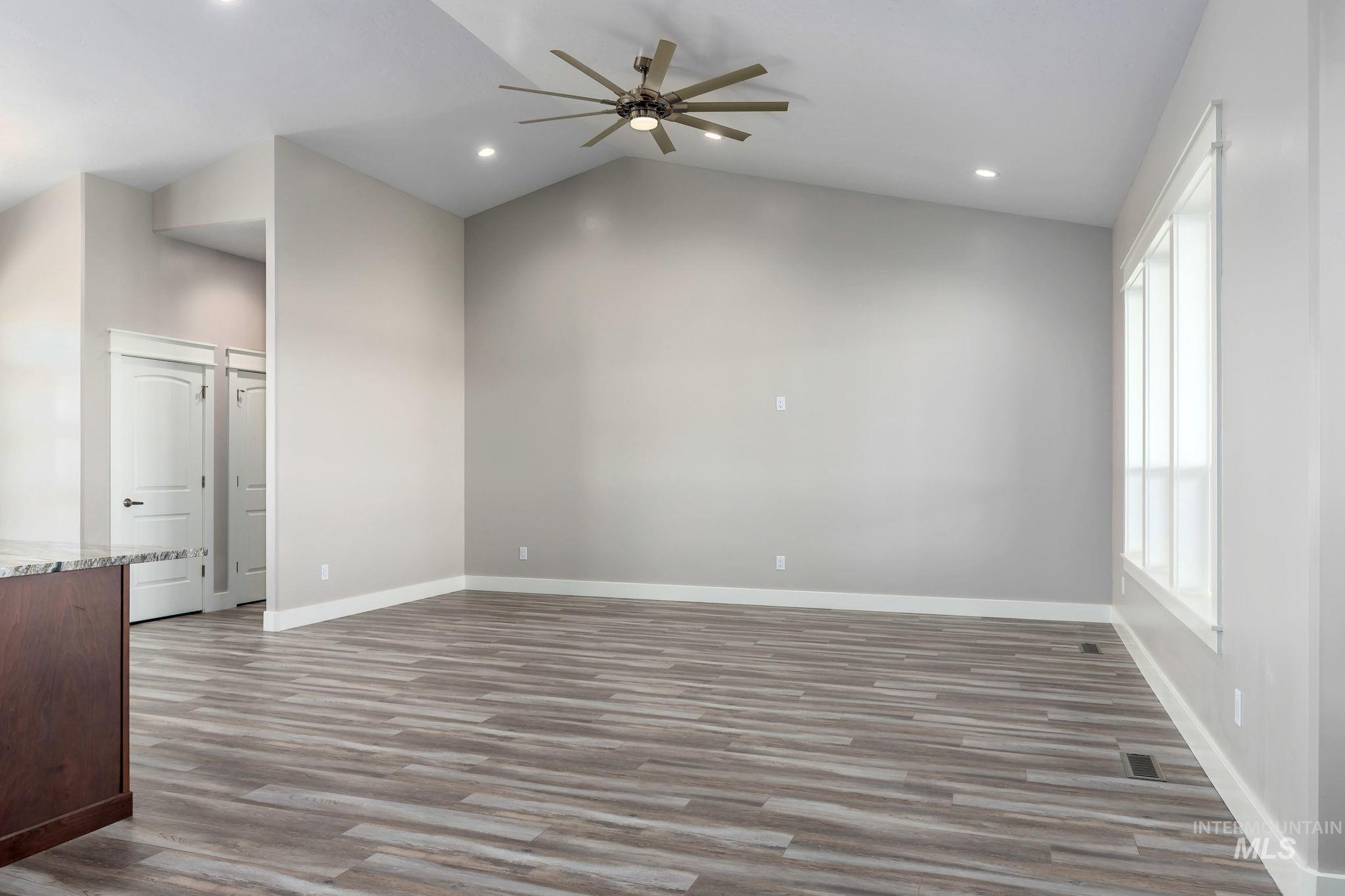 Unfurnished living room with ceiling fan, wood finished floors, vaulted ceiling, and recessed lighting