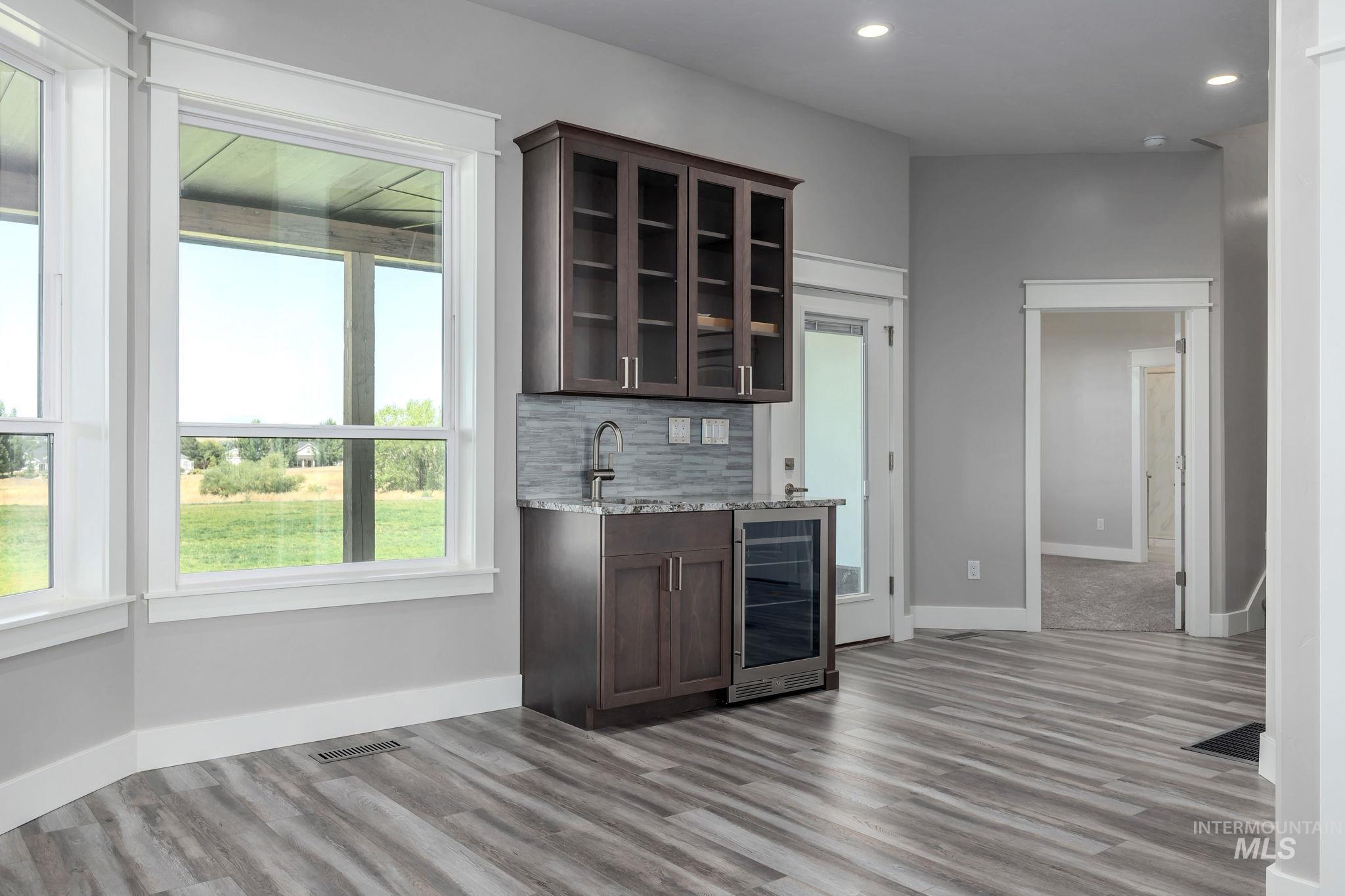 Indoor wet bar featuring wine cooler, recessed lighting, light wood finished floors, and tasteful backsplash