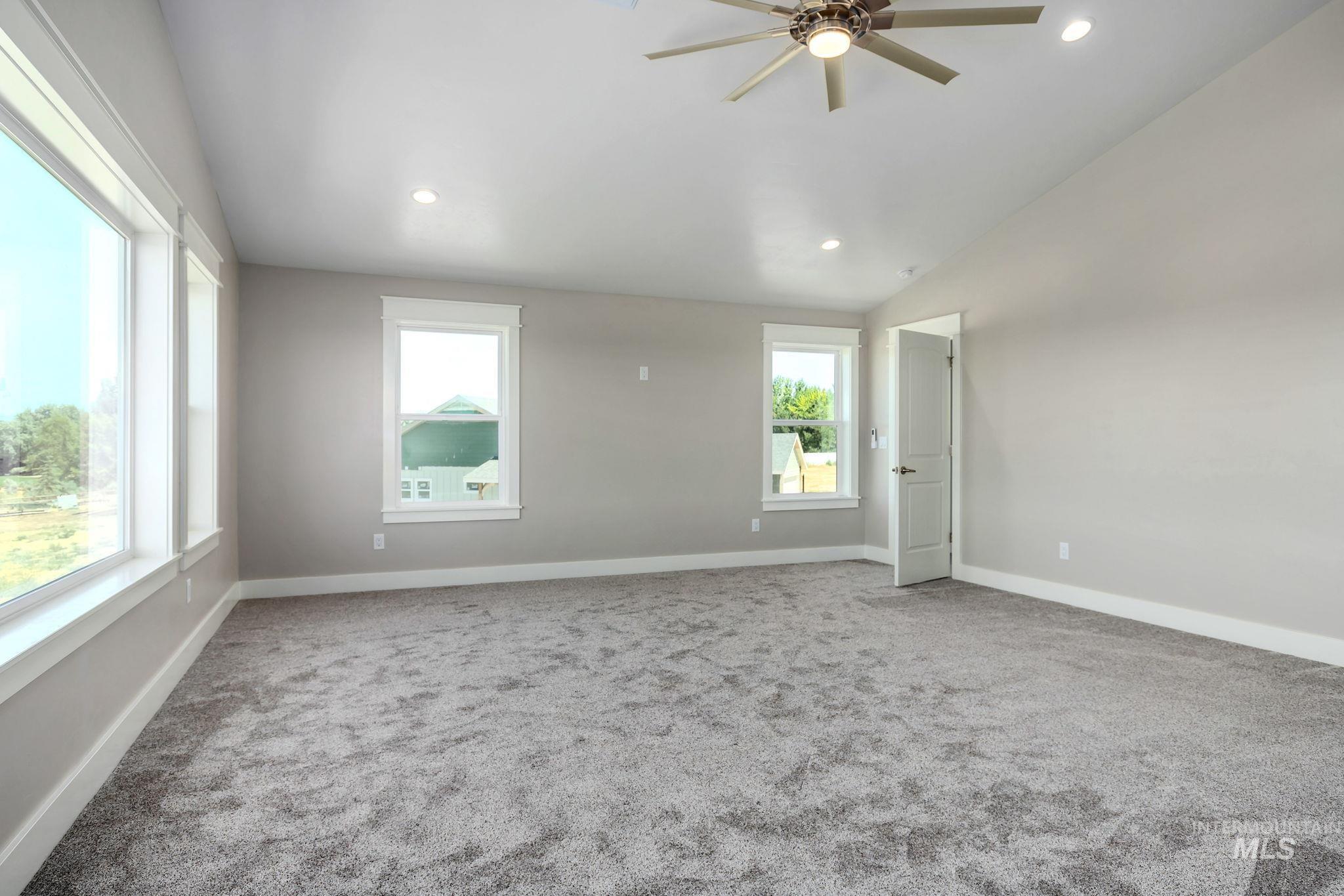 Empty room with healthy amount of natural light, ceiling fan, carpet flooring, recessed lighting, and lofted ceiling