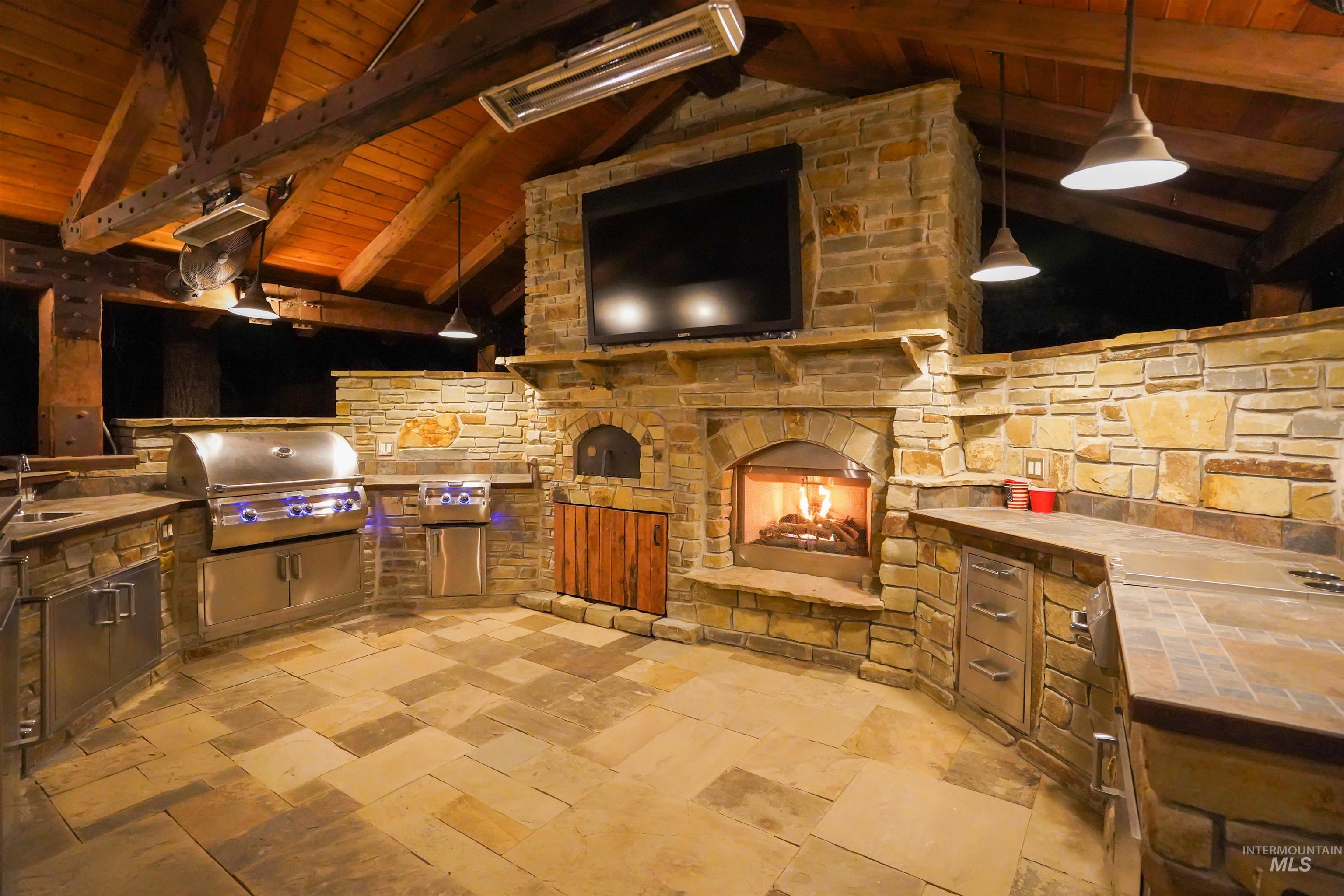 View of patio with a stone fireplace and area for grilling