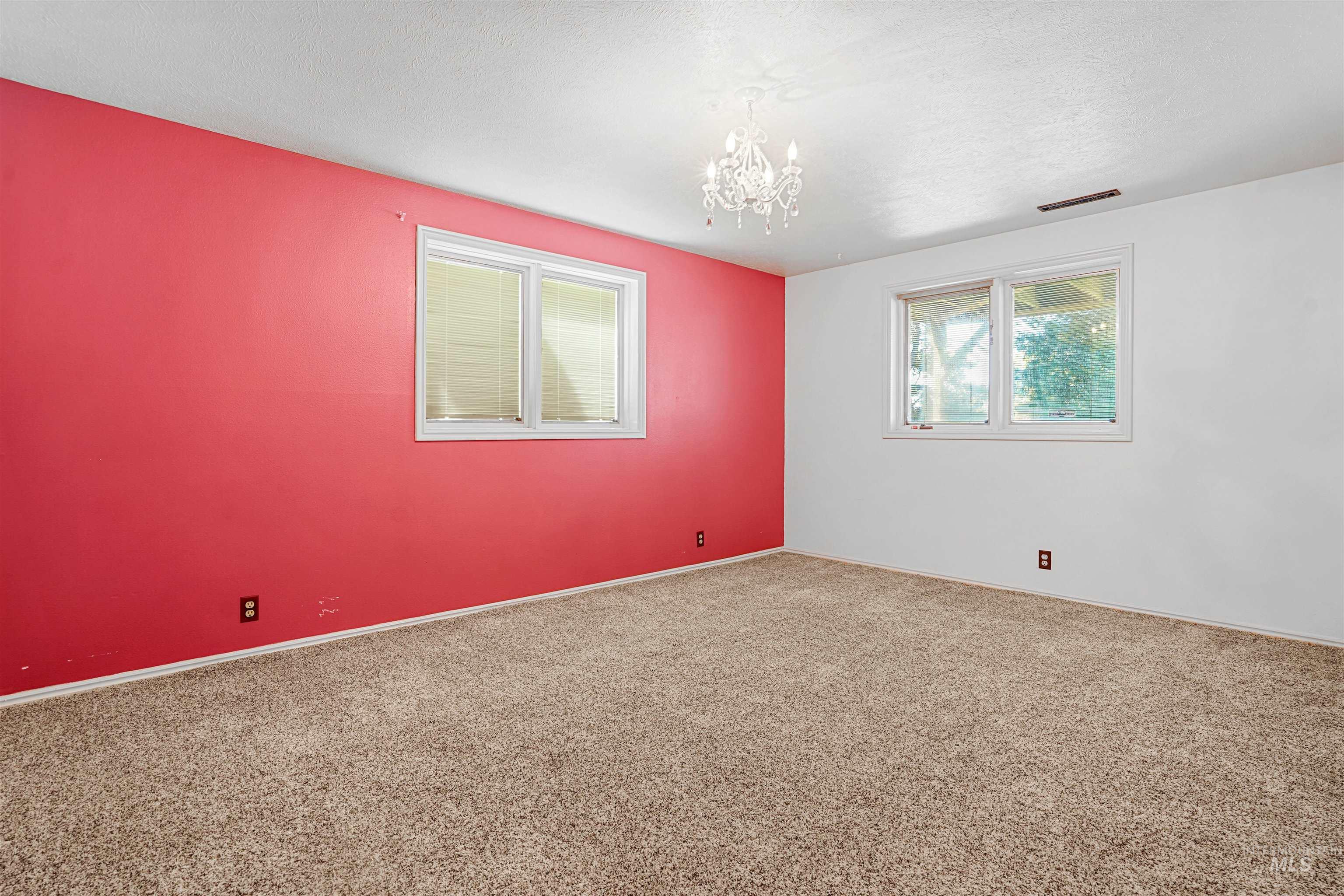 Unfurnished room featuring a chandelier, carpet floors, and a textured ceiling