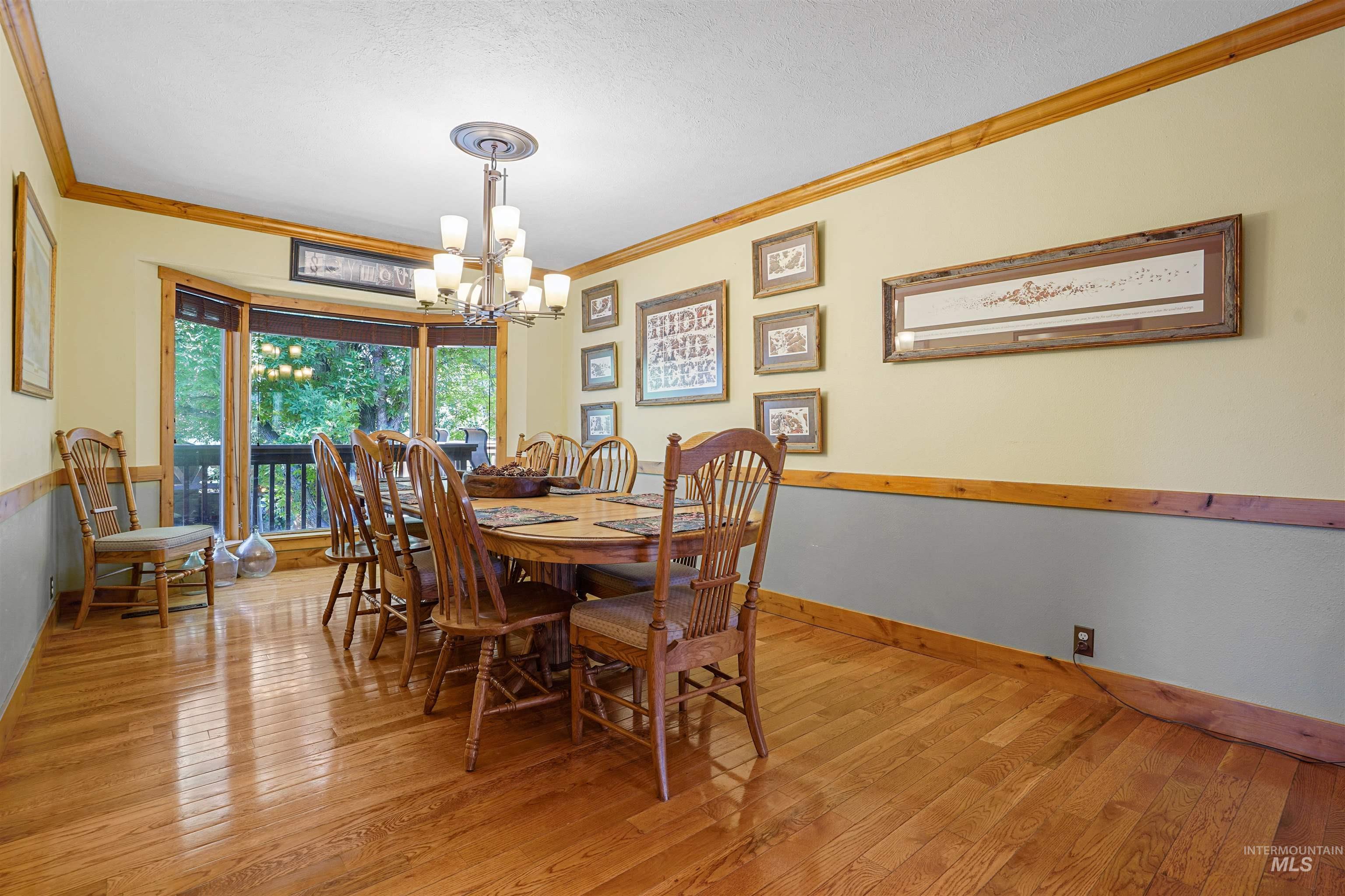 Dining room with crown molding, a chandelier, hardwood / wood-style floors, and a textured ceiling