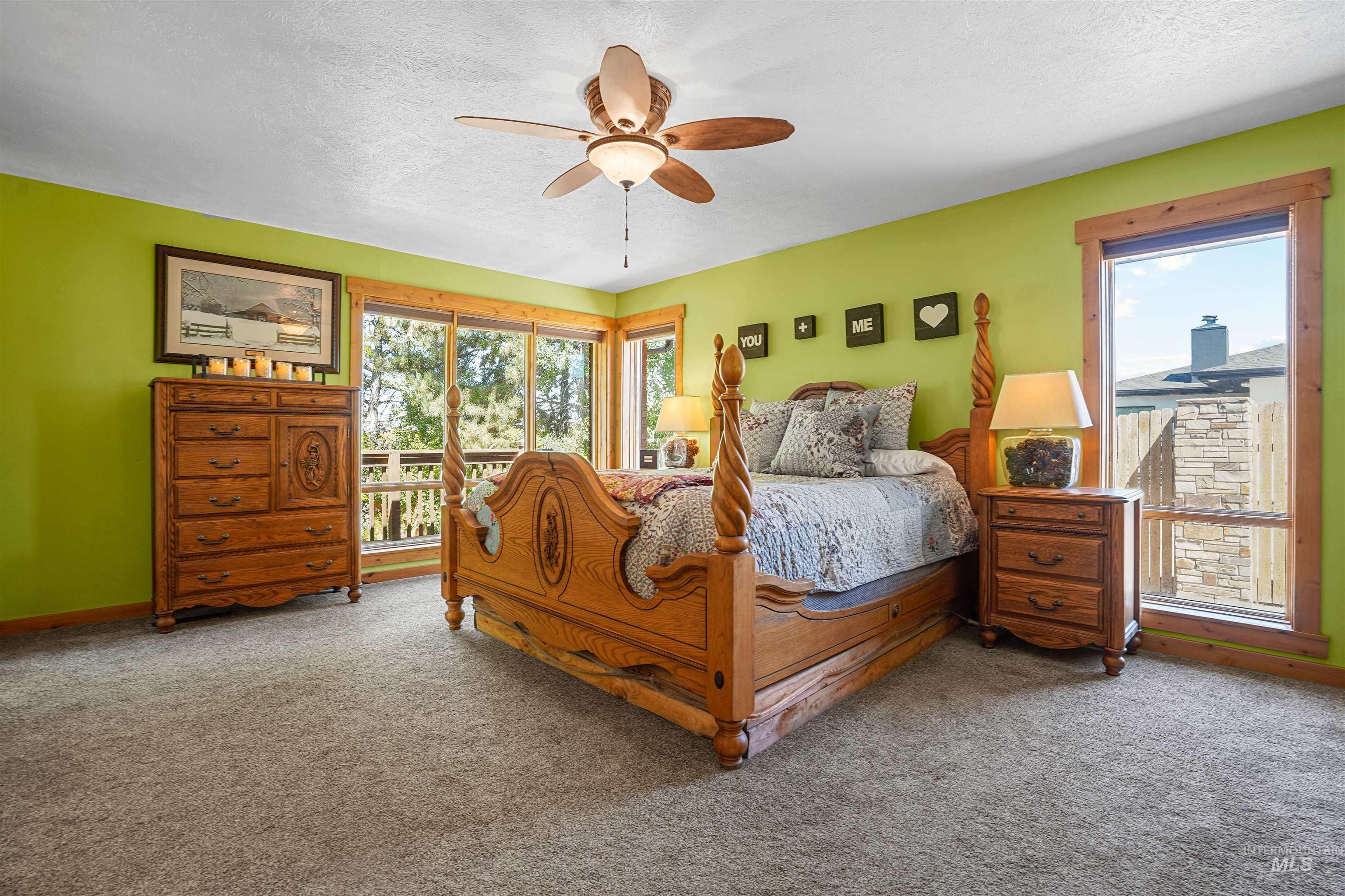 Carpeted bedroom with multiple windows, a textured ceiling, a ceiling fan, and access to exterior