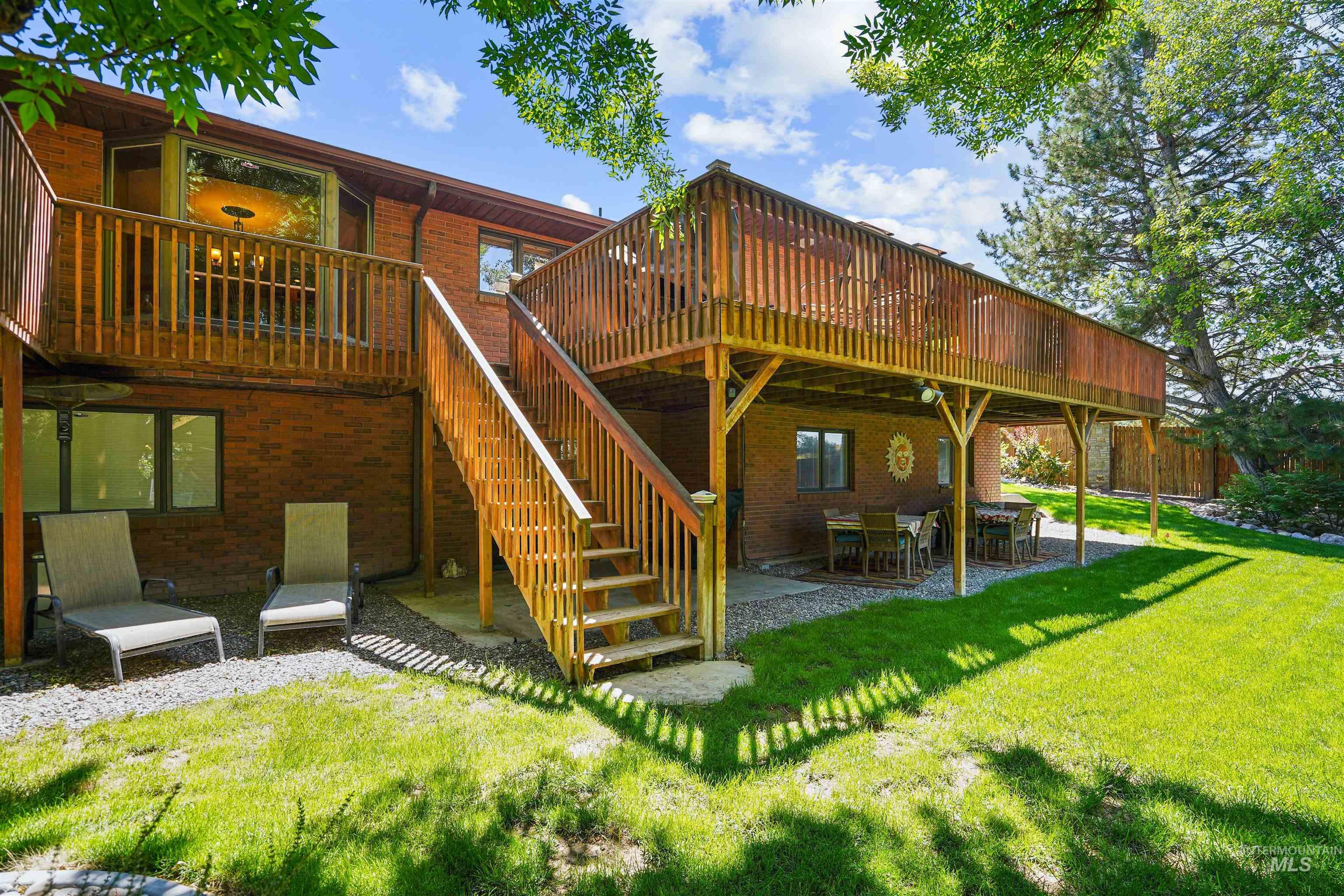 Rear view of house with a patio, brick siding, a wooden deck, and stairs