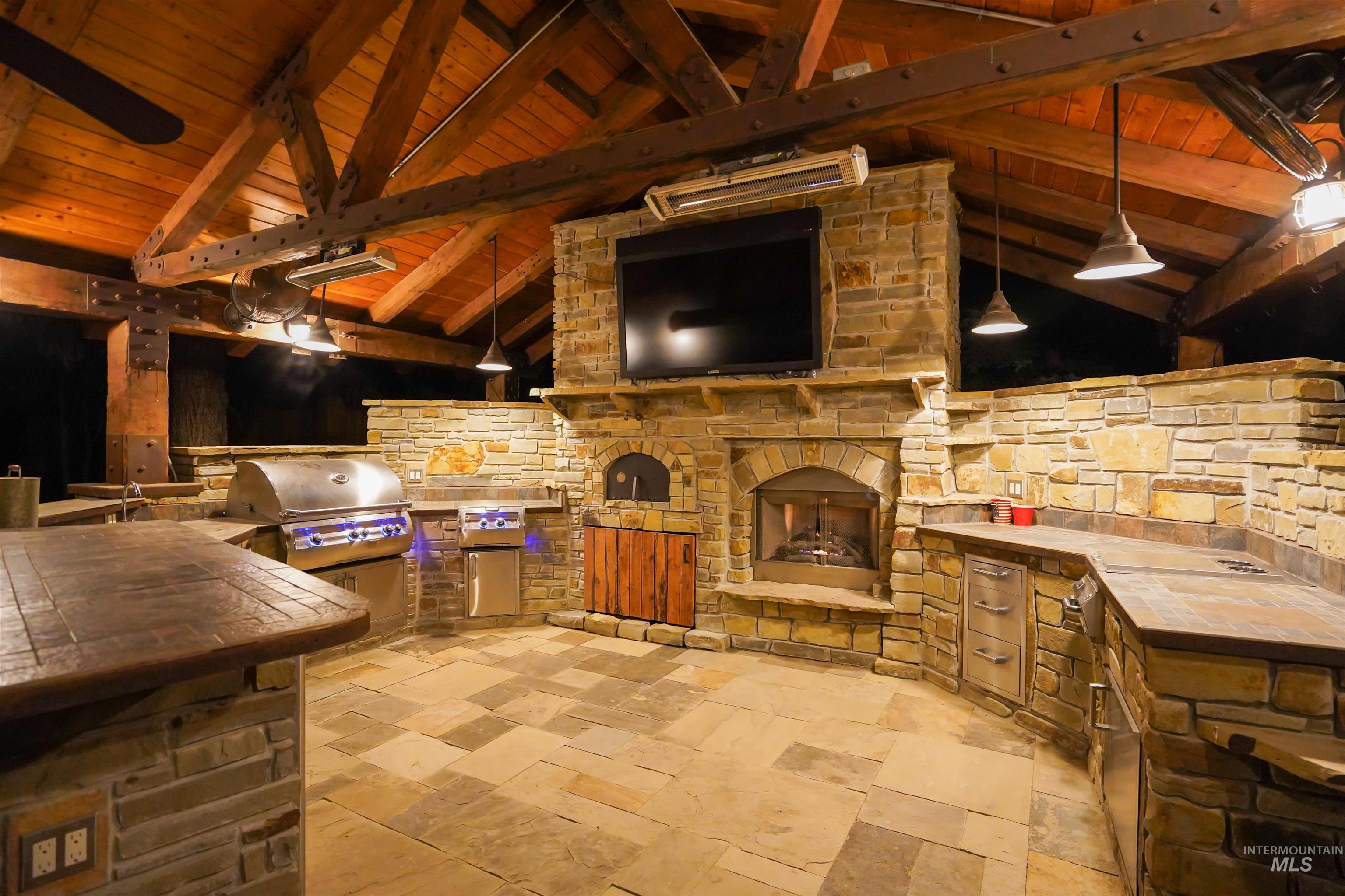 View of patio / terrace featuring a stone fireplace, area for grilling, a gazebo, and ceiling fan