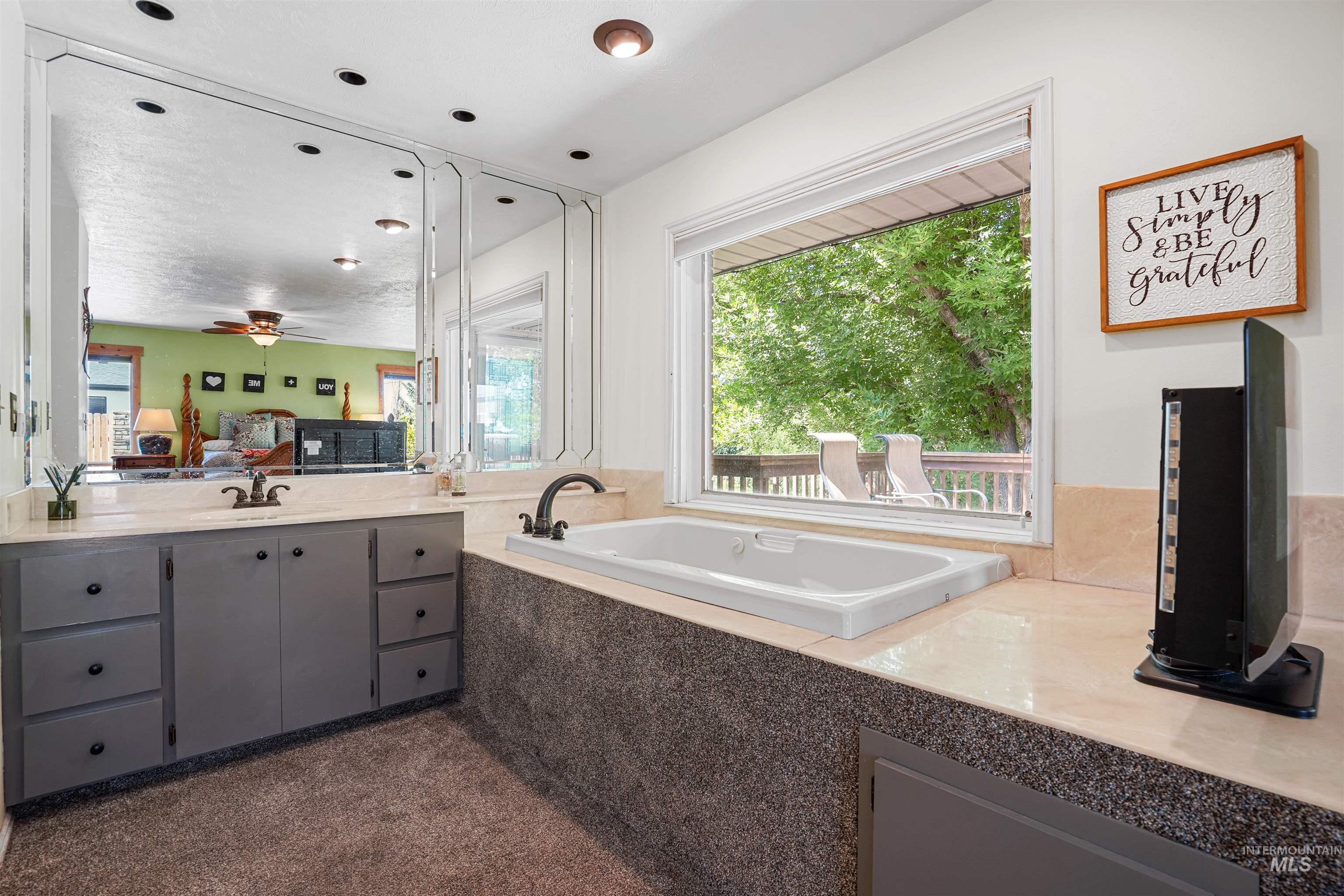 Full bathroom with vanity, a garden tub, and a ceiling fan