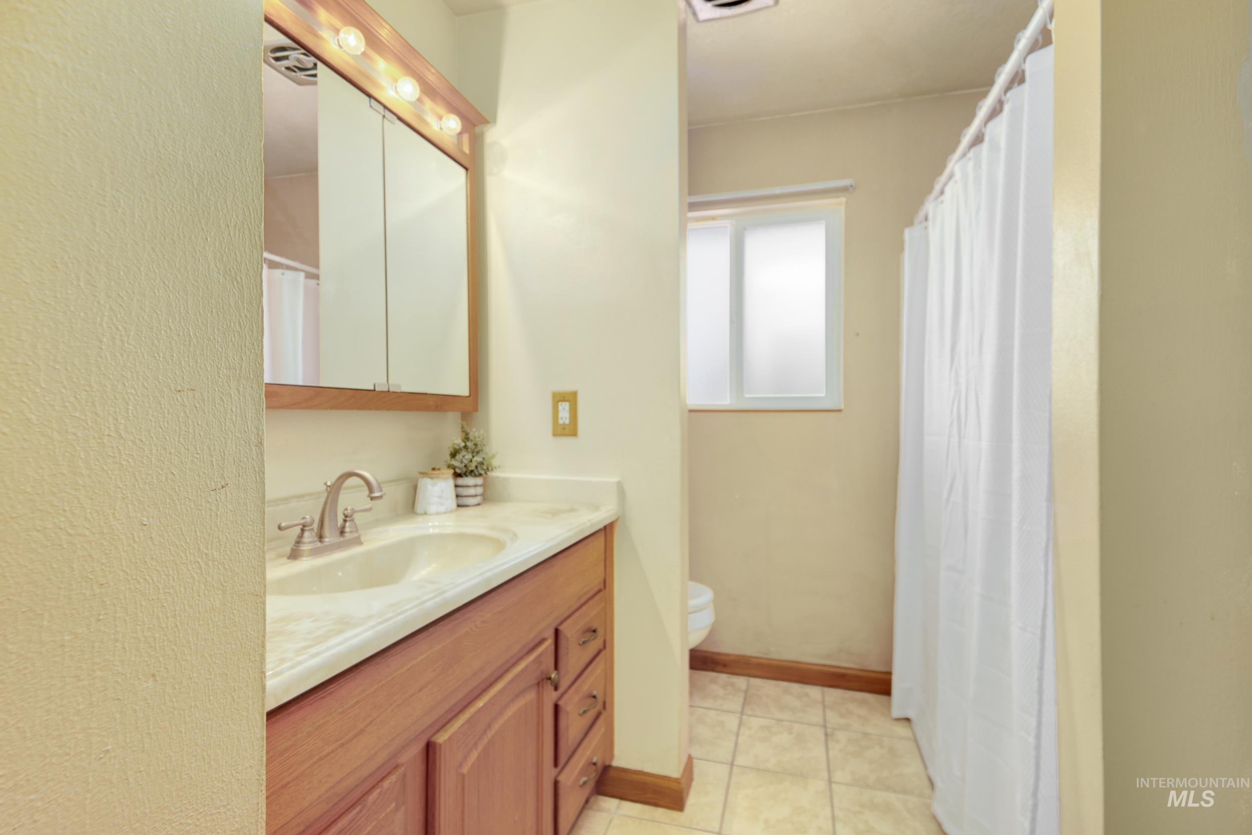 Bathroom featuring vanity, light tile patterned flooring, and a shower with shower curtain