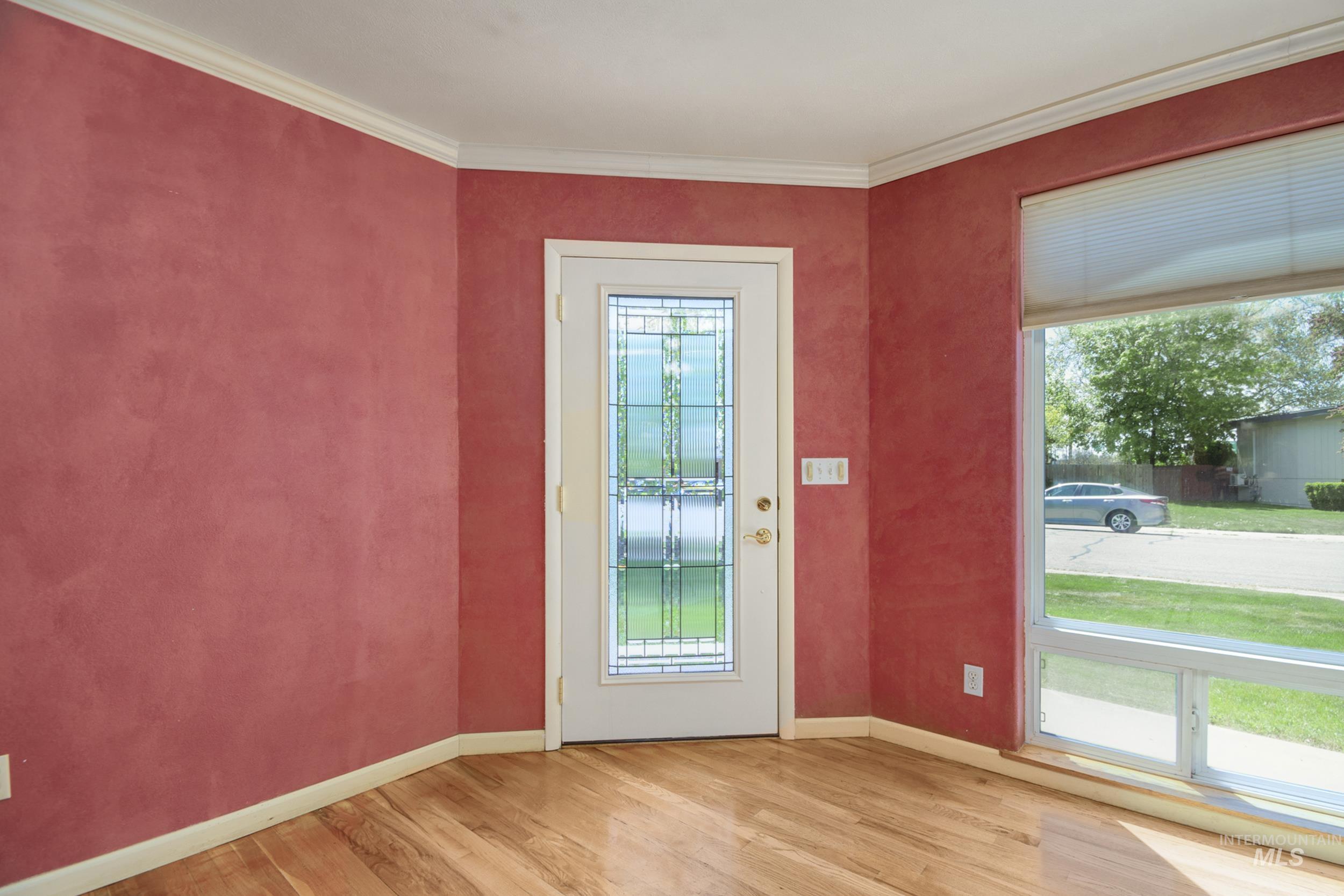 Doorway to outside featuring ornamental molding and wood finished floors