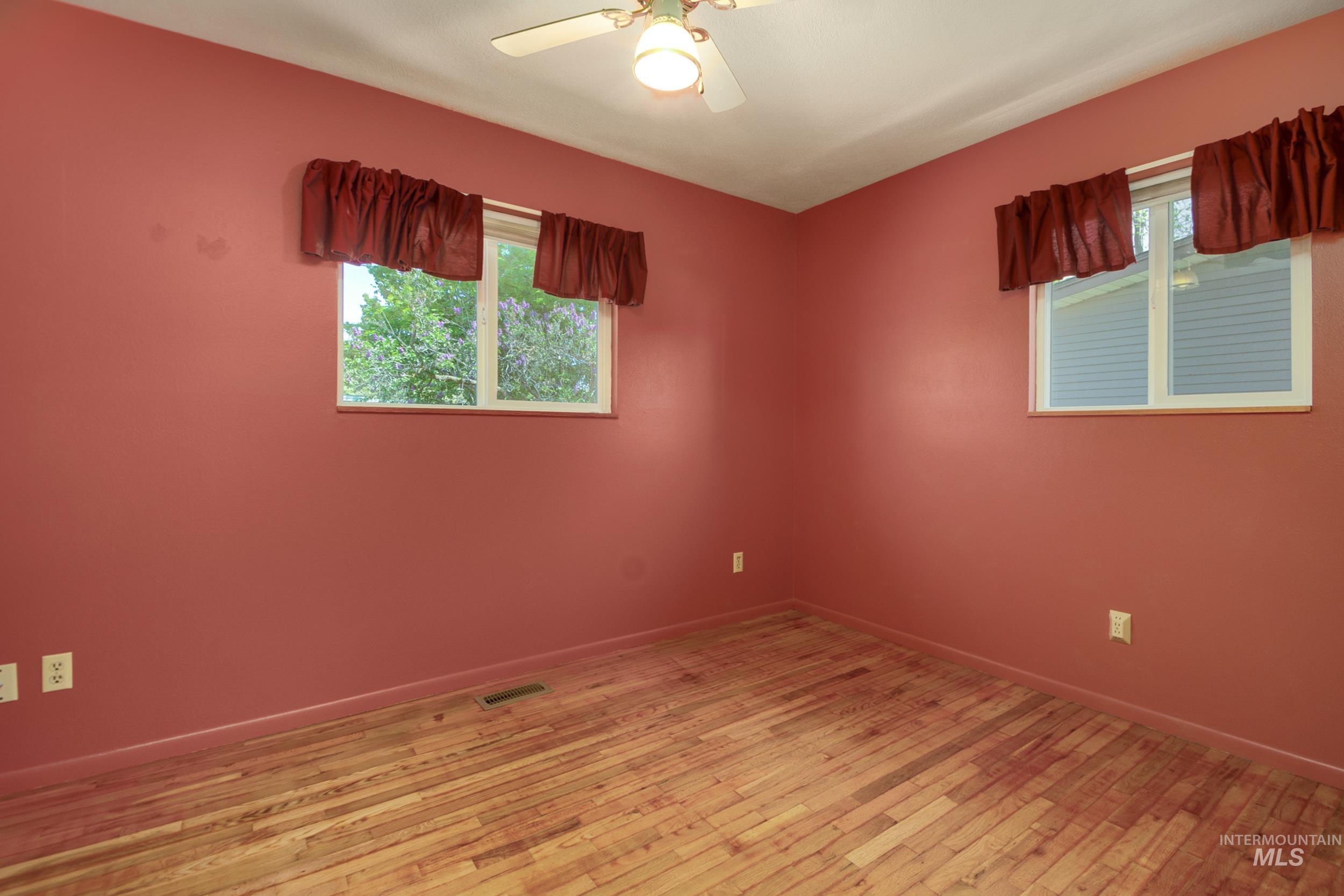 Empty room with healthy amount of natural light, light wood-type flooring, and ceiling fan