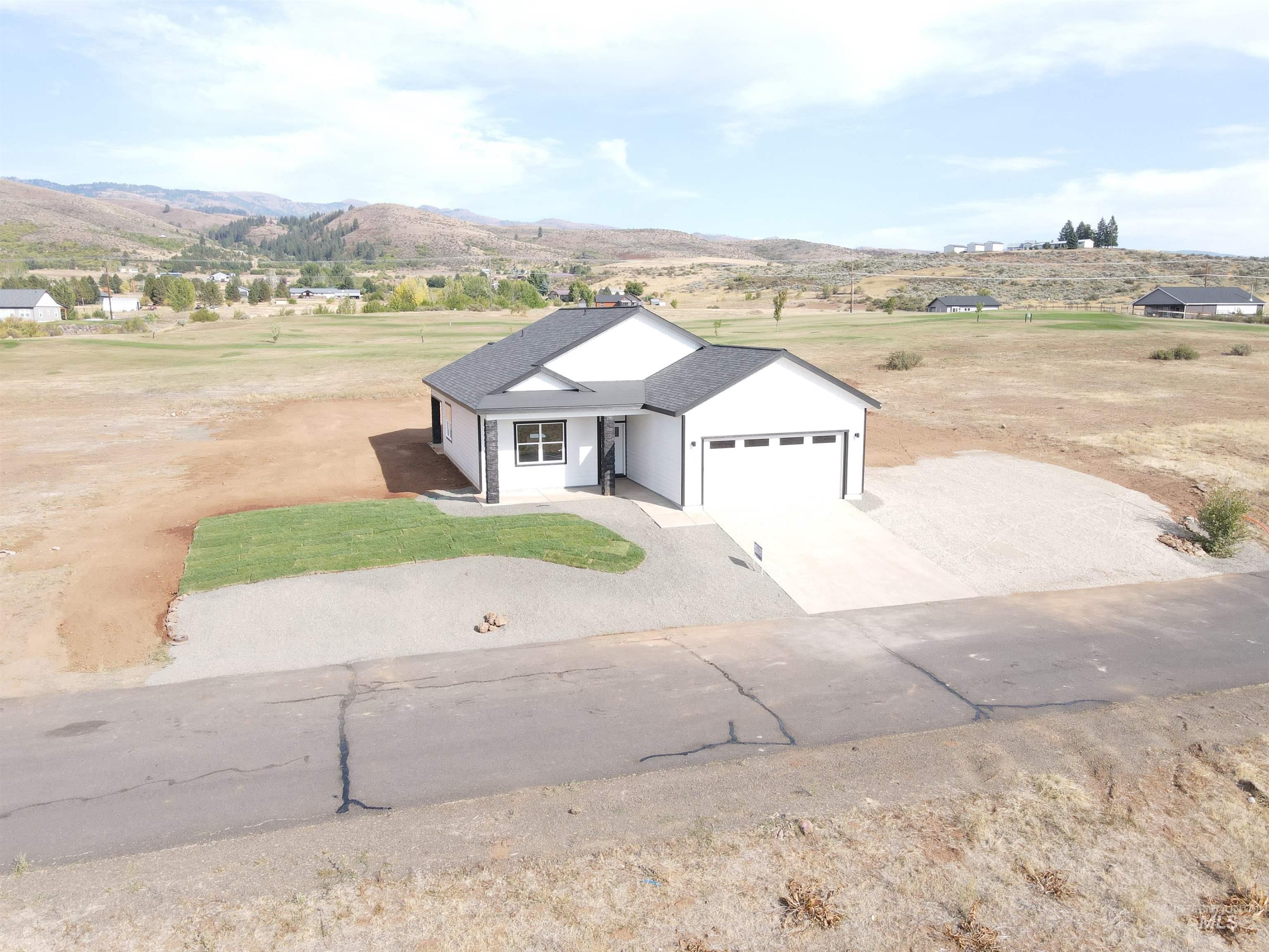 View of front of property with driveway, an attached garage, a mountain view, and a view of countryside