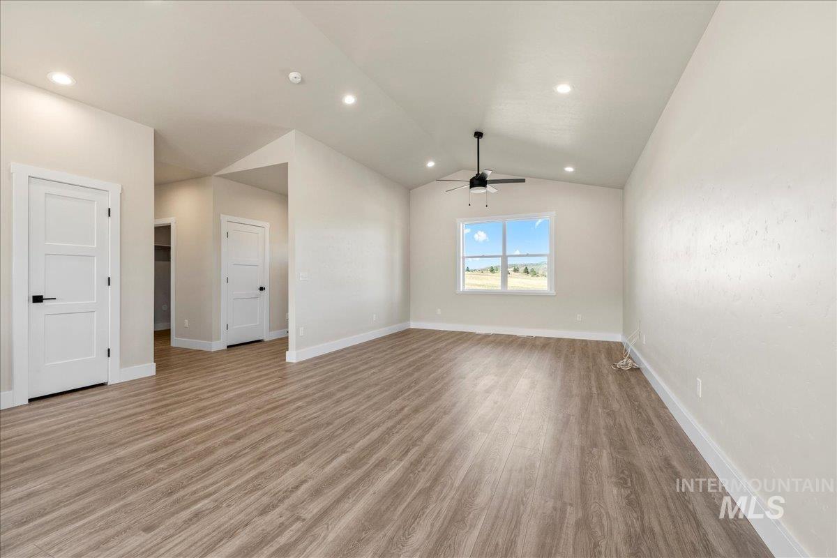 Unfurnished living room with light wood finished floors, lofted ceiling, a ceiling fan, and recessed lighting