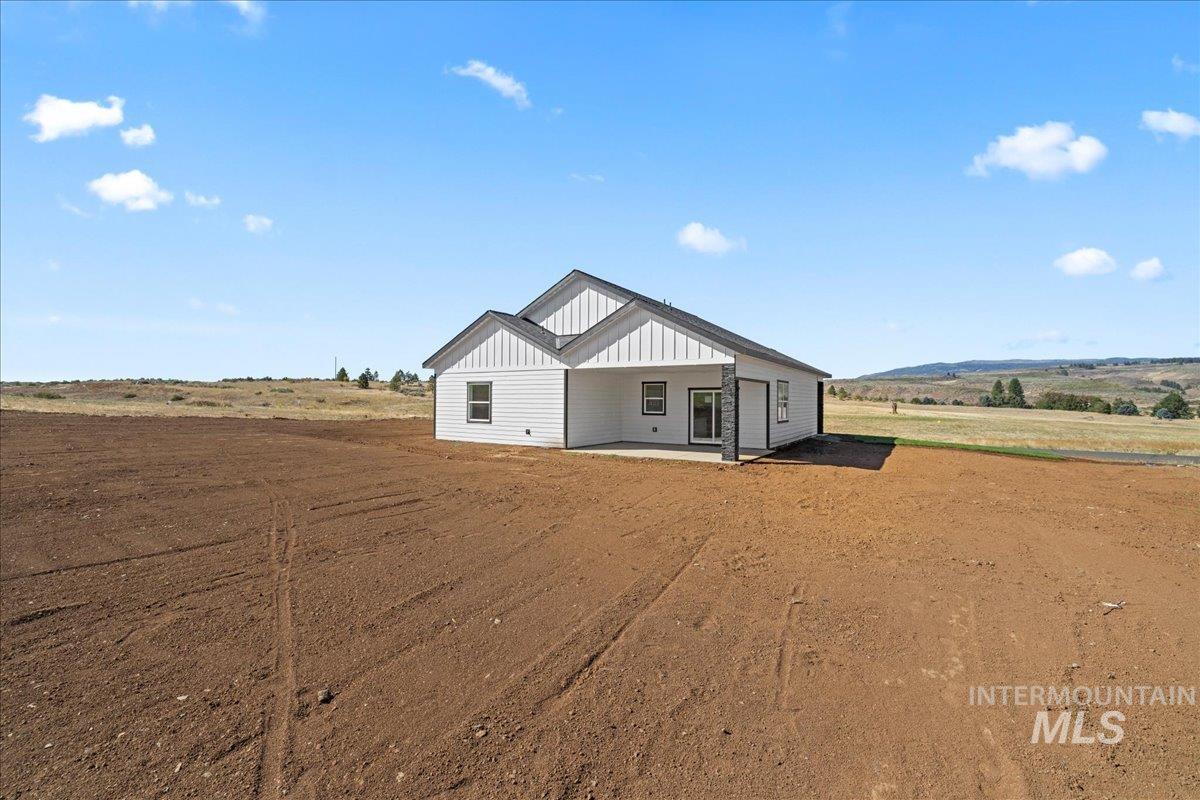 Modern farmhouse style home featuring a patio area, board and batten siding, and a rural view