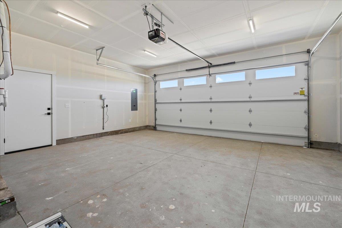 Garage featuring a garage door opener and electric panel