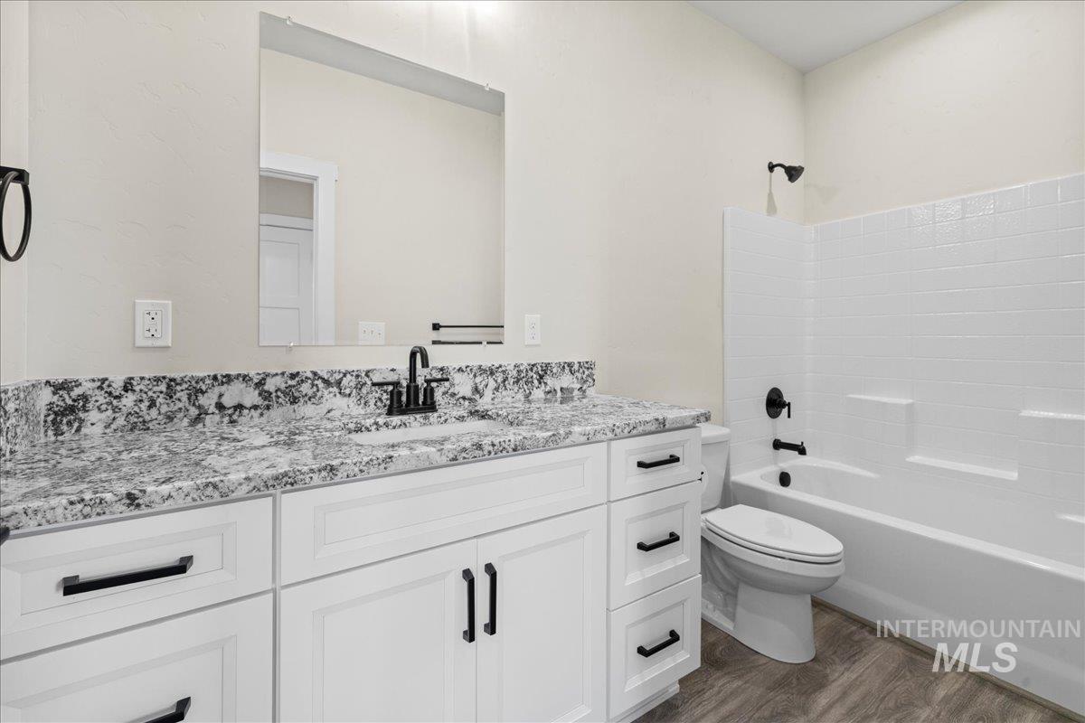 Bathroom featuring dark wood-style flooring, tub / shower combination, and vanity