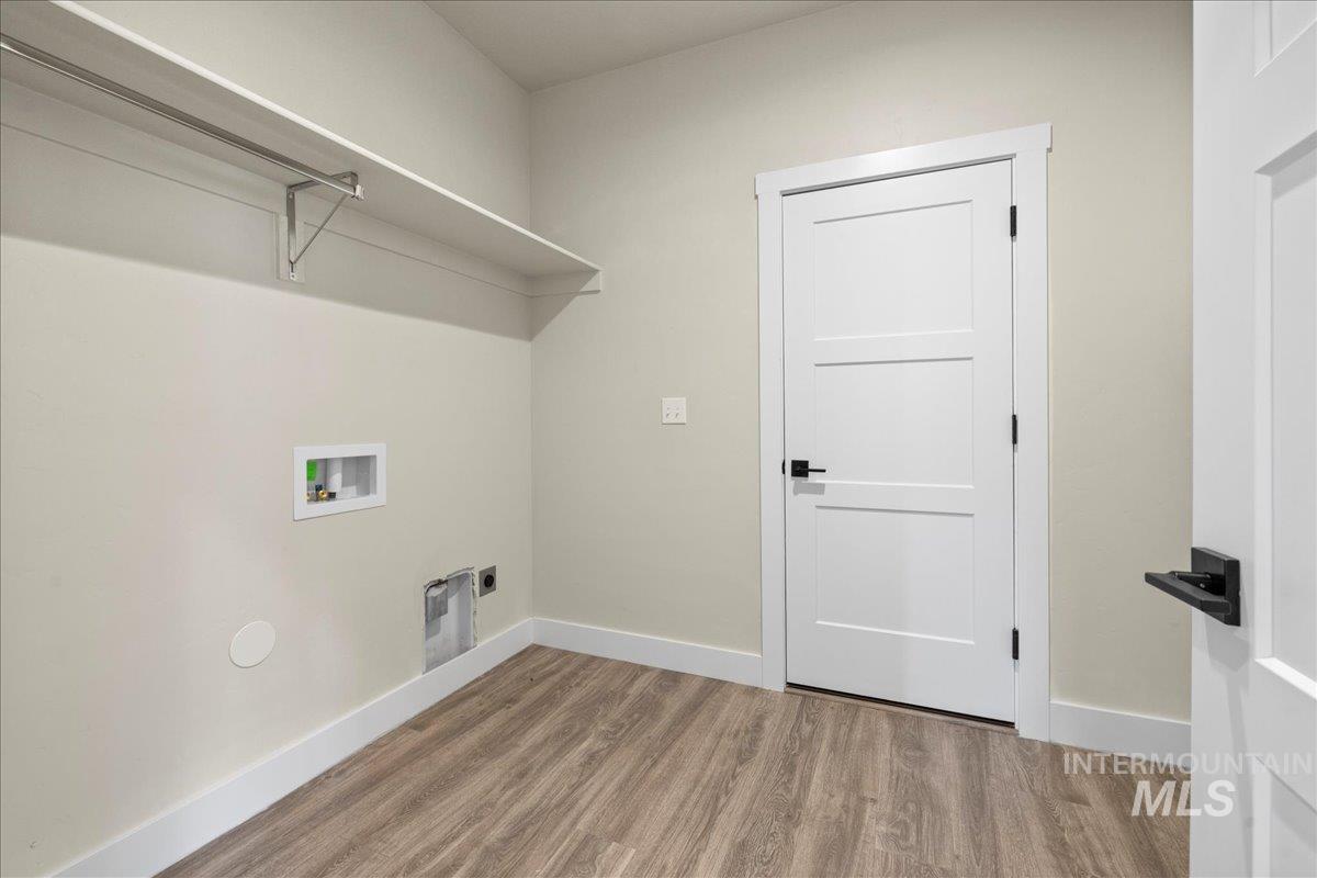 Washroom featuring light wood finished floors, hookup for a washing machine, and electric dryer hookup