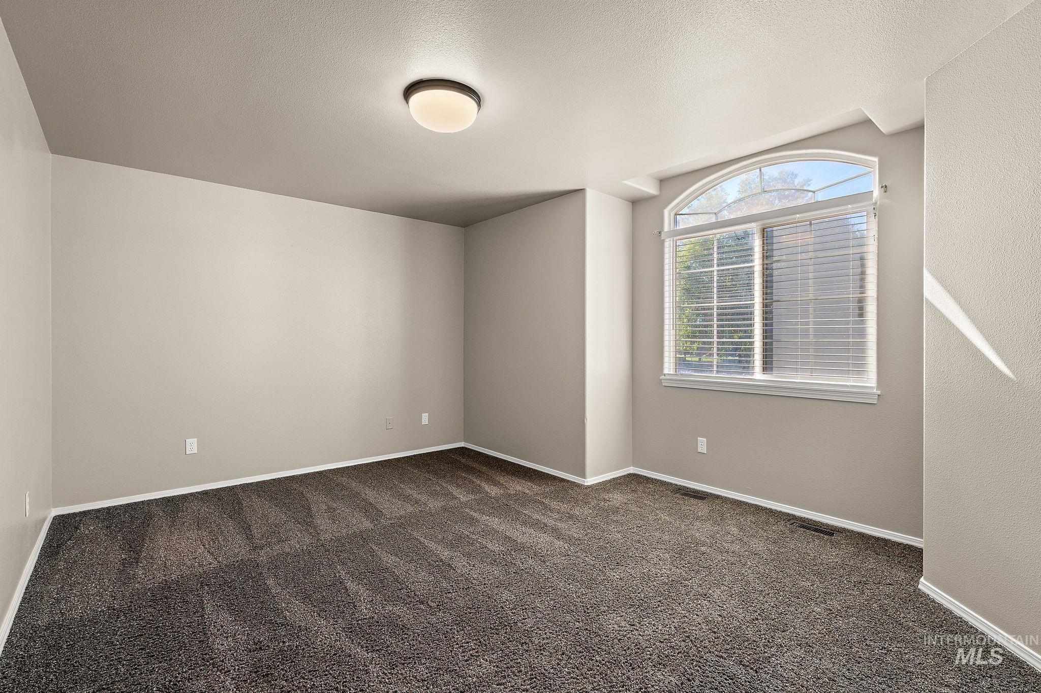 Spare room featuring dark colored carpet and a textured ceiling