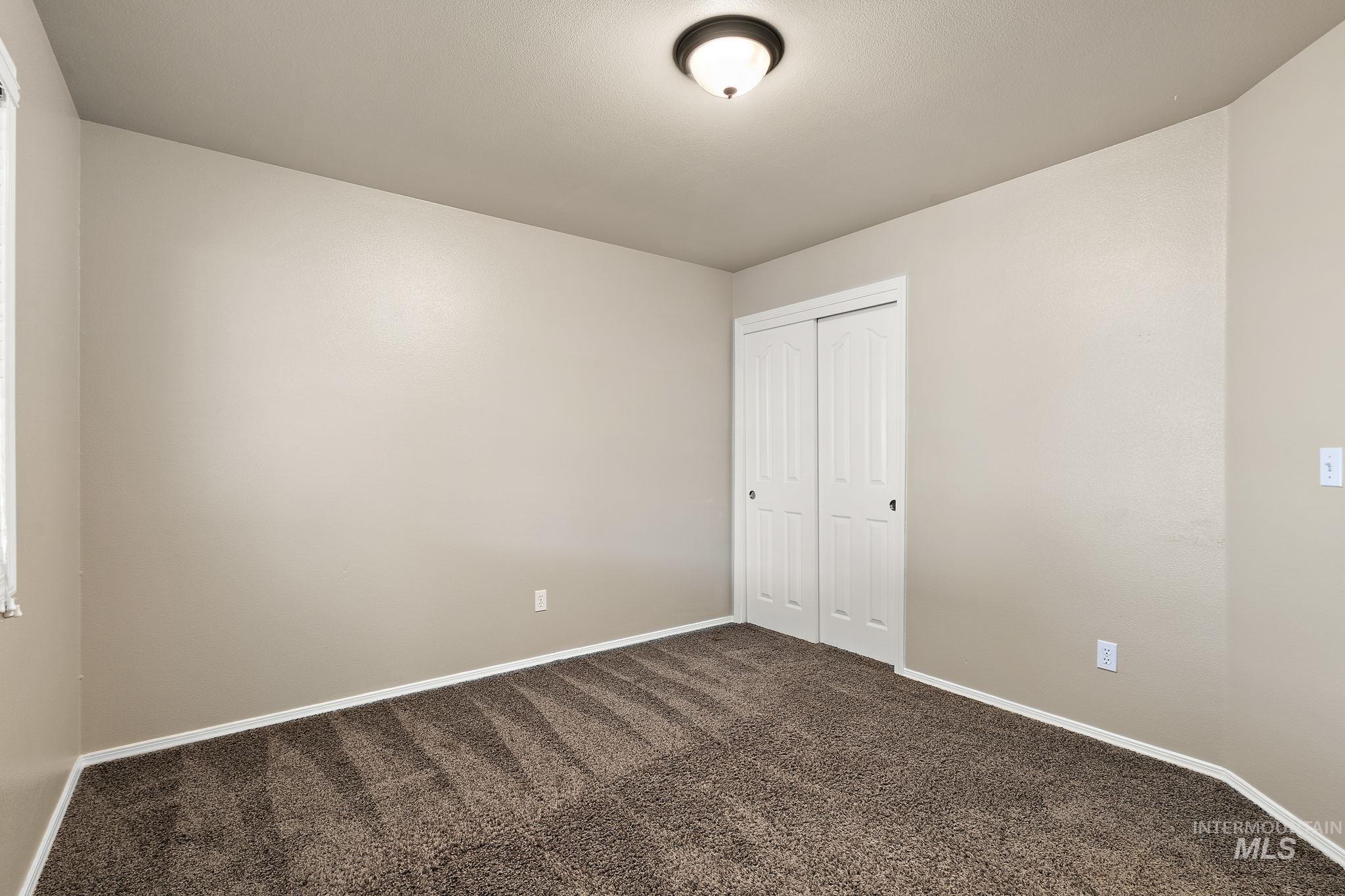 Unfurnished bedroom featuring dark carpet and a closet