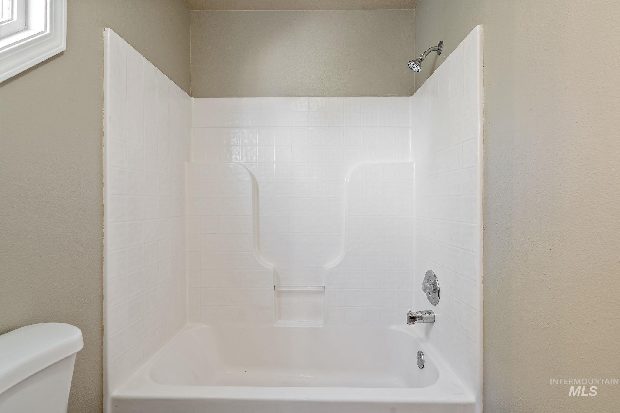 Bathroom with shower / bathtub combination and a textured wall