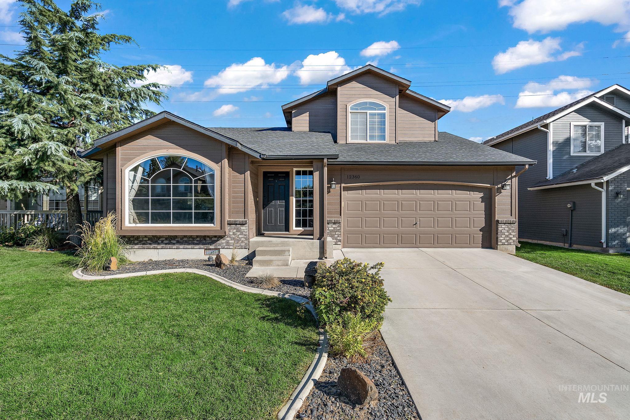 Traditional home with a shingled roof, a front lawn, concrete driveway, brick siding, and an attached garage