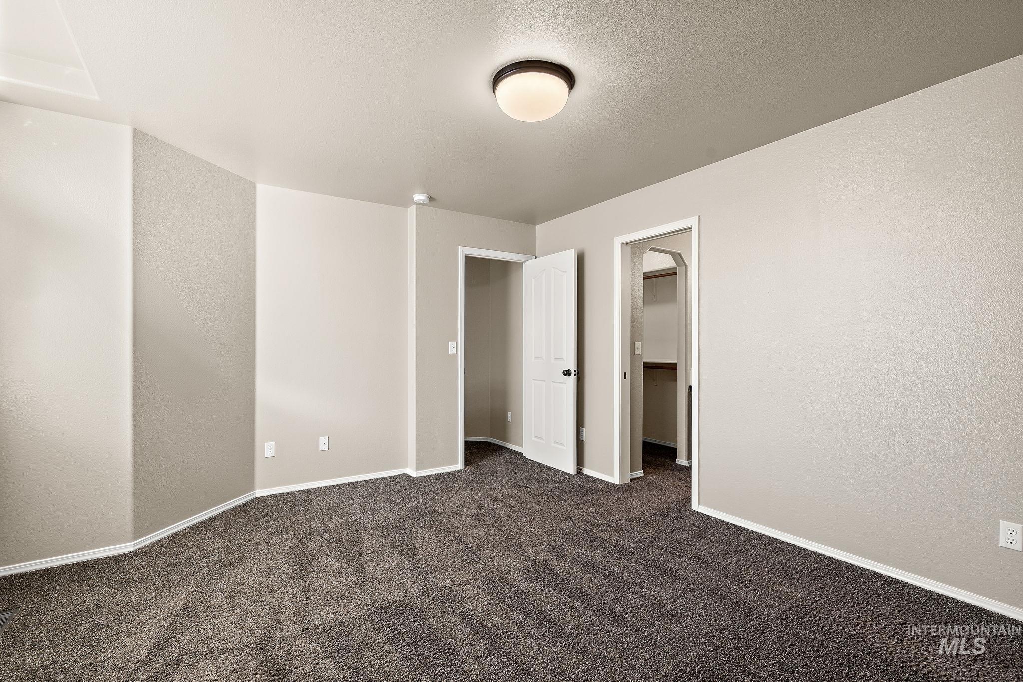 Unfurnished bedroom with a spacious closet and dark carpet