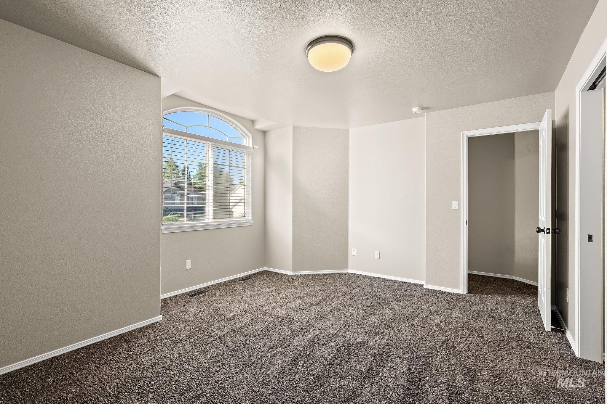 Spare room with dark carpet and a textured ceiling