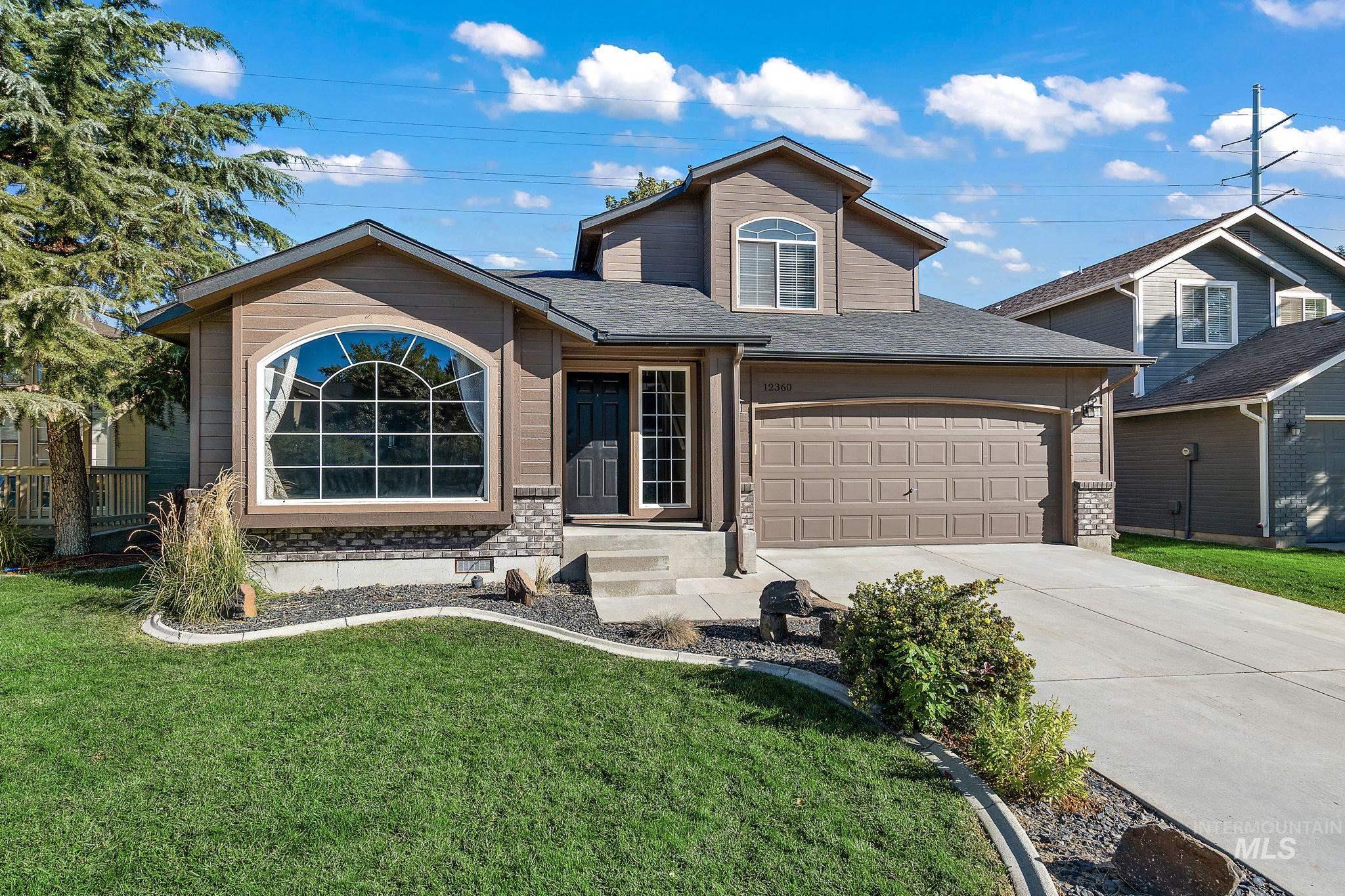 View of front facade featuring a shingled roof, driveway, a garage, and a front yard