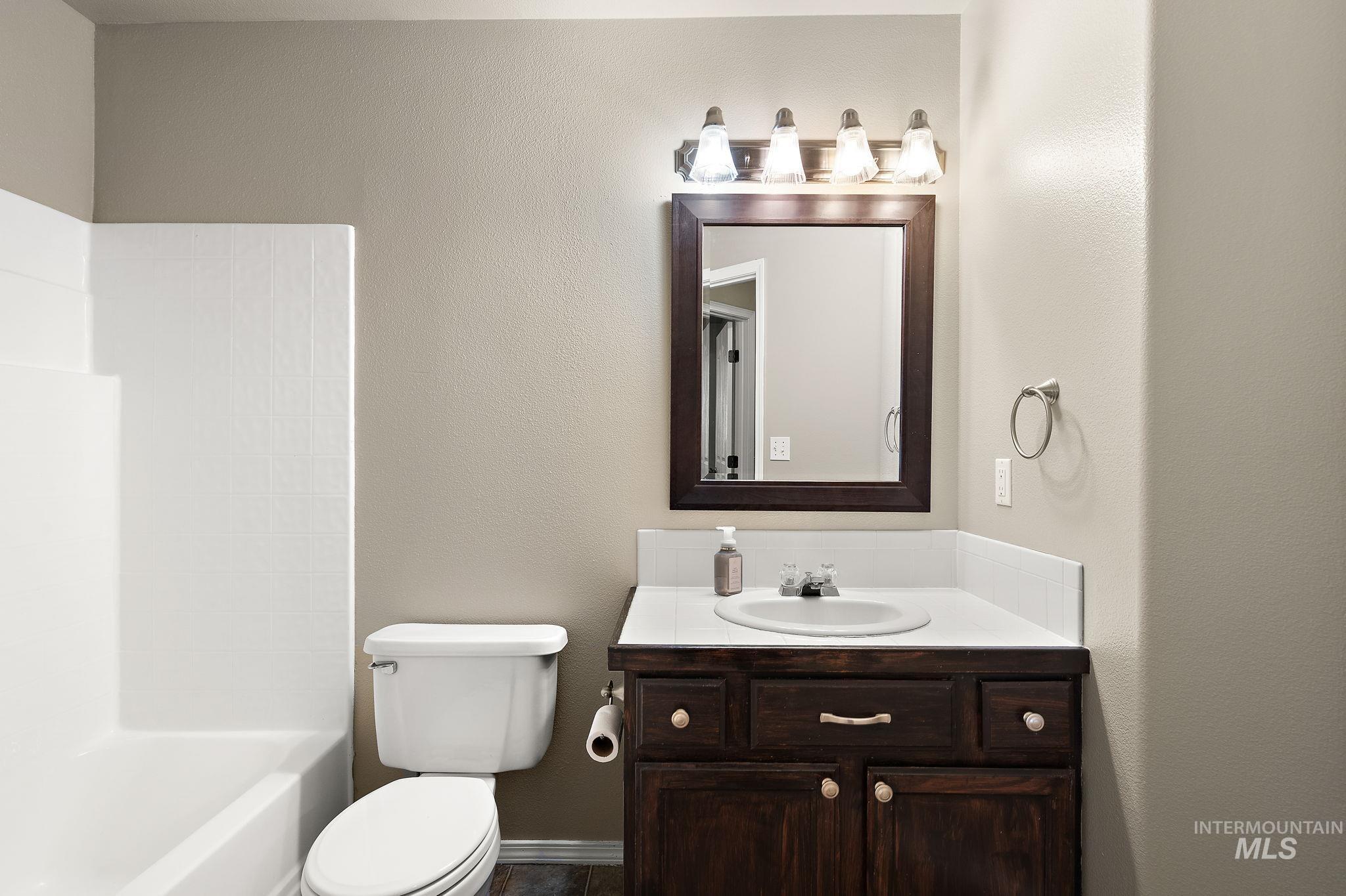 Full bathroom featuring vanity, bathing tub / shower combination, and a textured wall