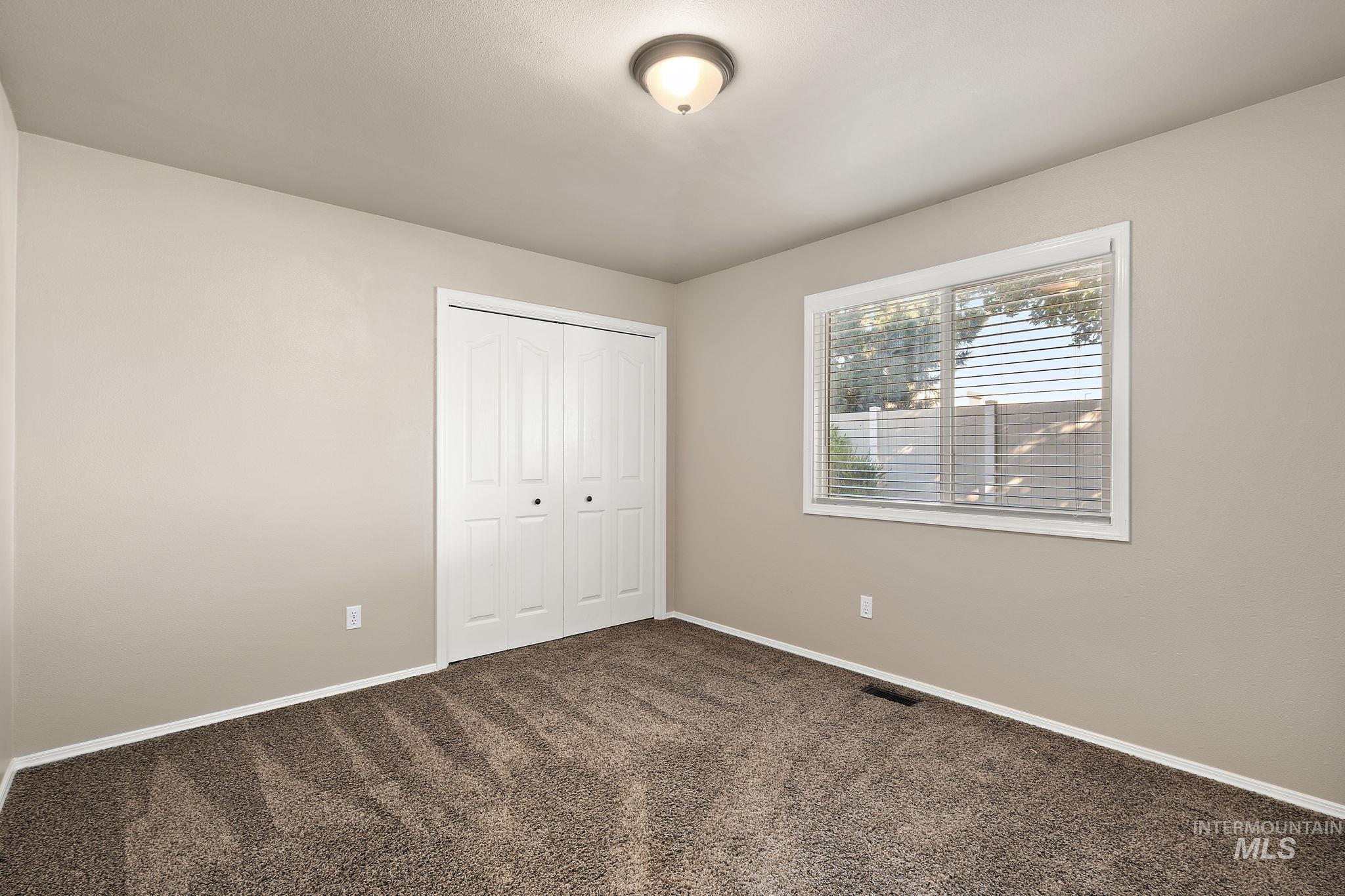 Unfurnished bedroom featuring dark carpet and a closet