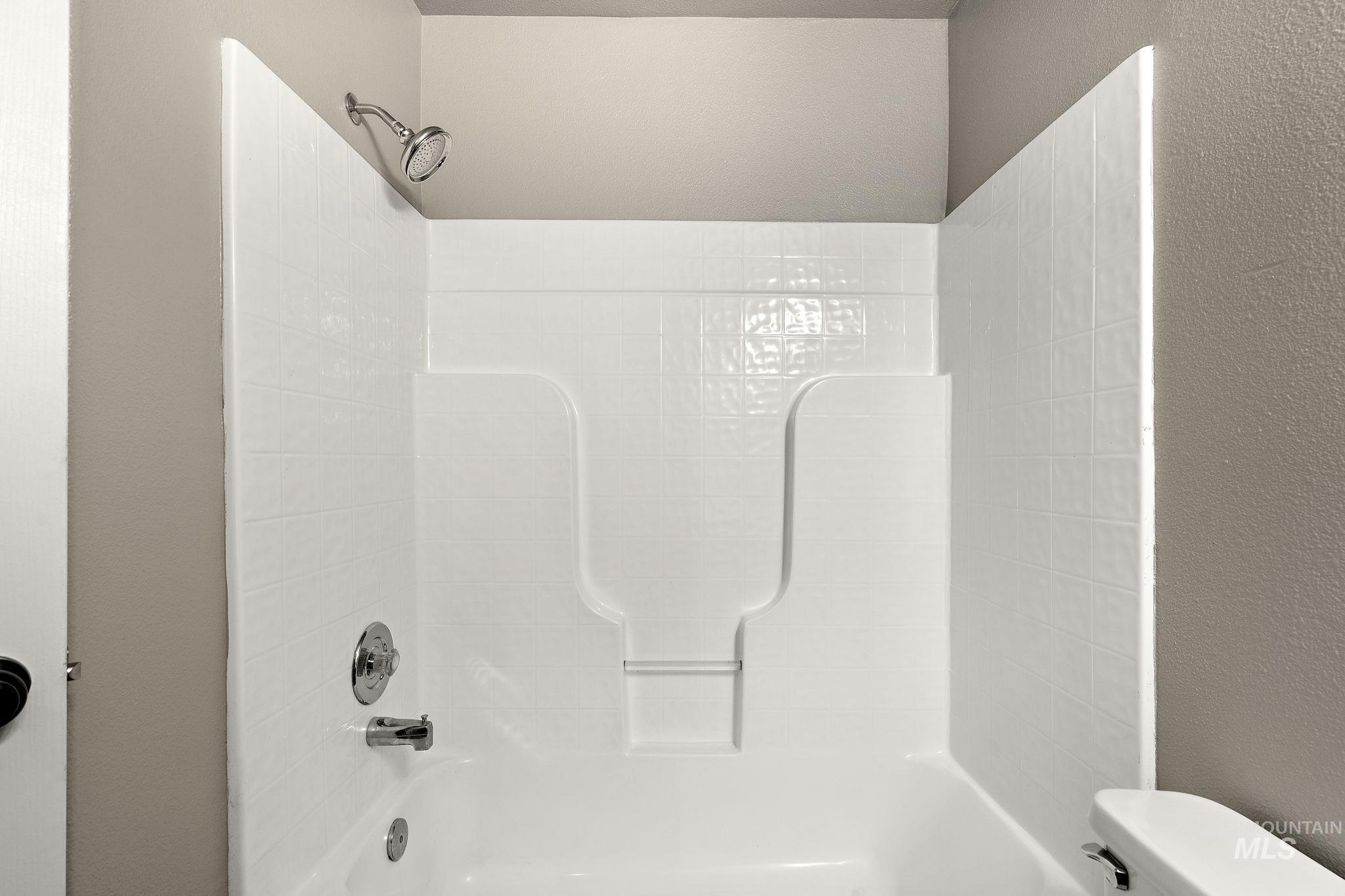 Bathroom featuring a textured wall and shower / tub combination