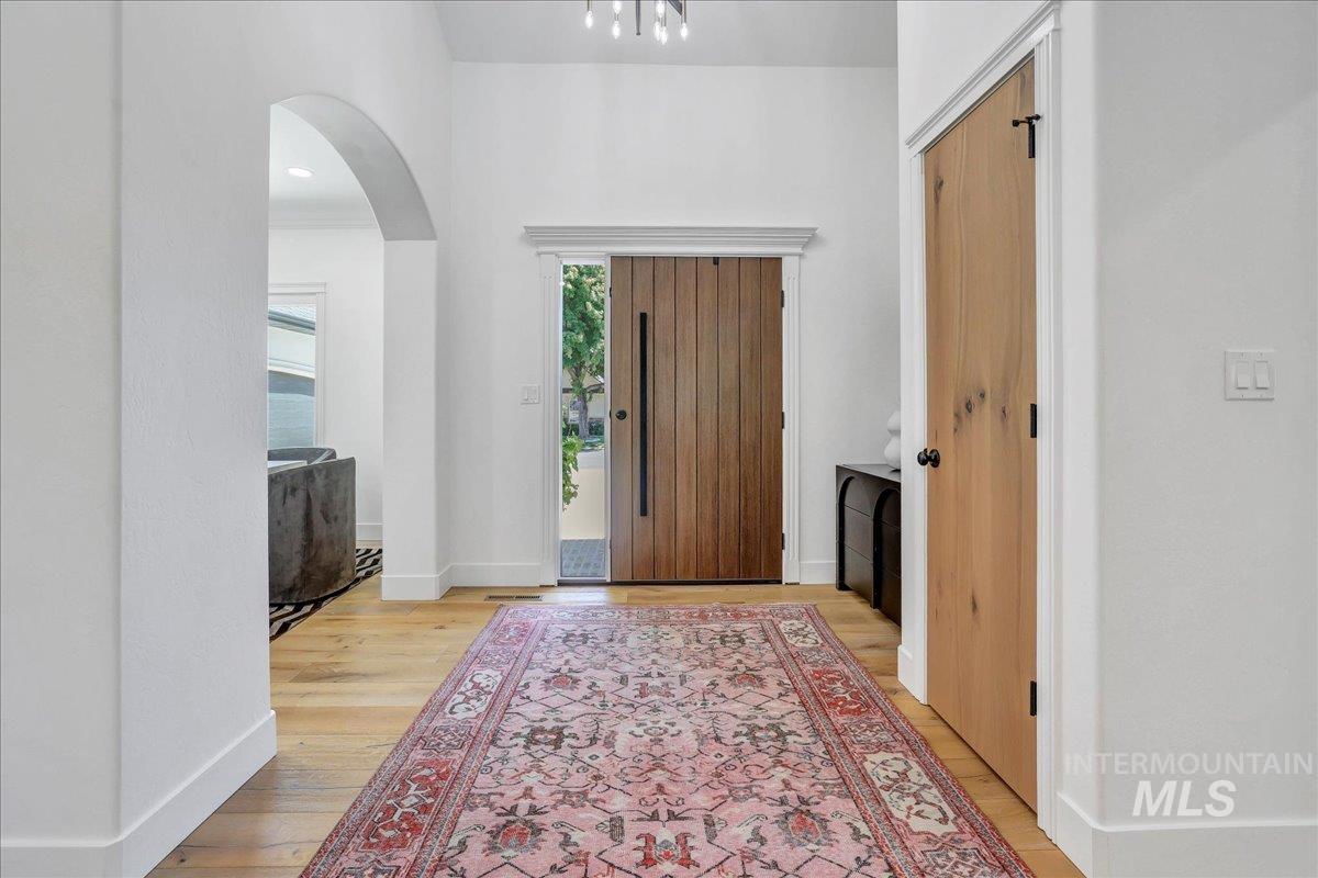 Foyer featuring arched walkways and light wood-style floors