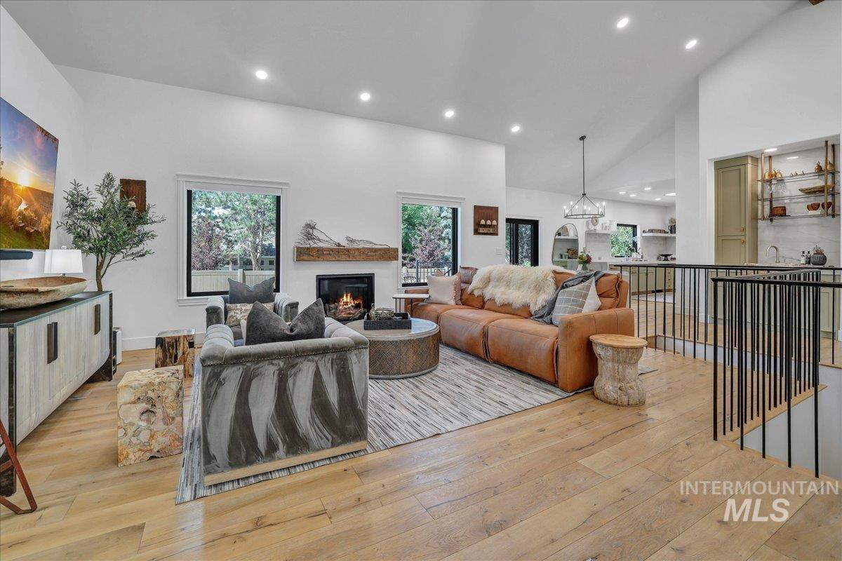 Living area with light wood finished floors, recessed lighting, a glass covered fireplace, and high vaulted ceiling