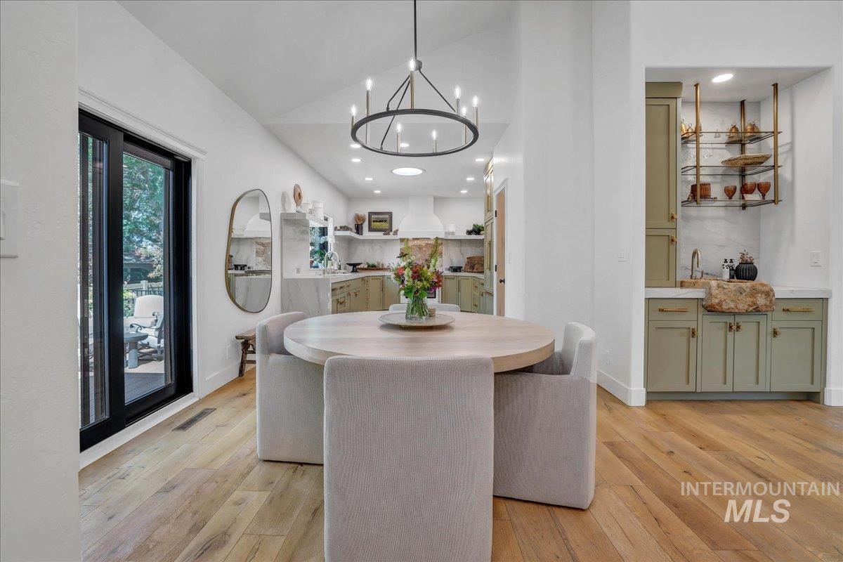Dining room with lofted ceiling, recessed lighting, light wood-type flooring, and a chandelier