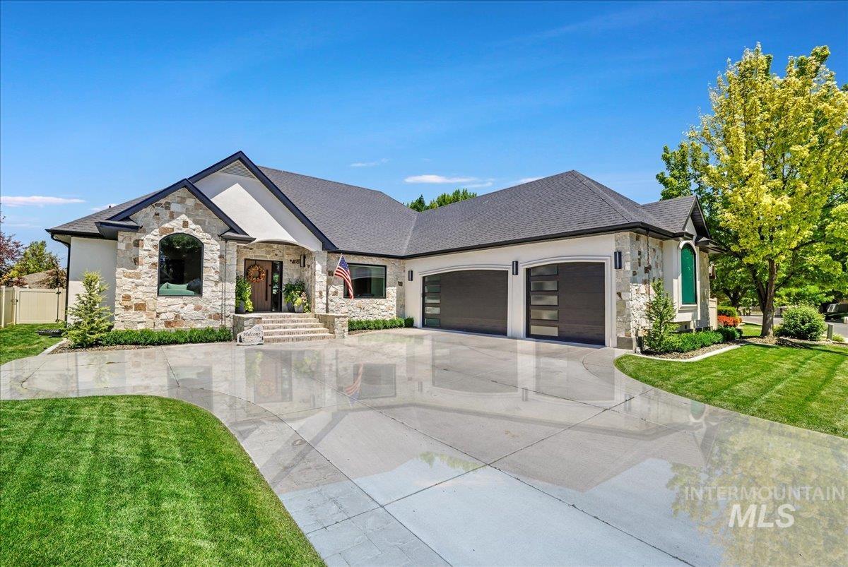 French provincial home featuring stone siding, an attached garage, a front lawn, and concrete driveway