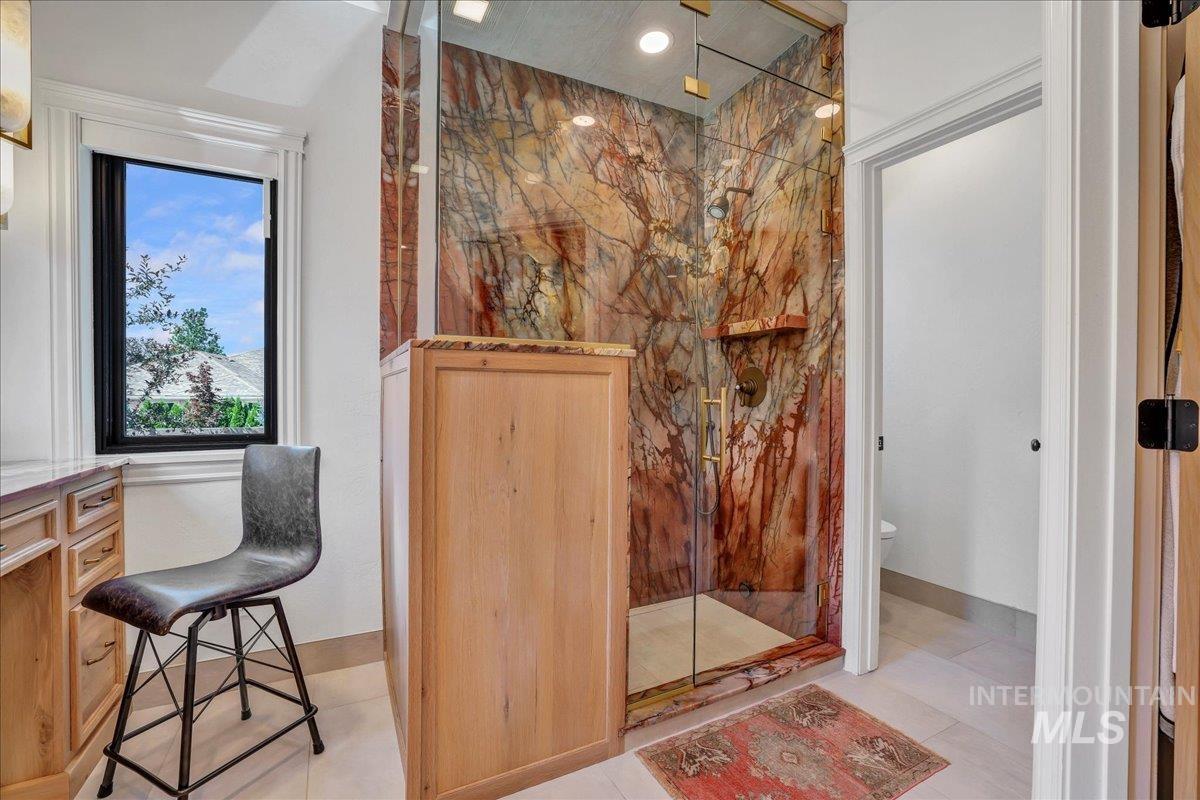 Bathroom with a marble finish shower and tile patterned floors