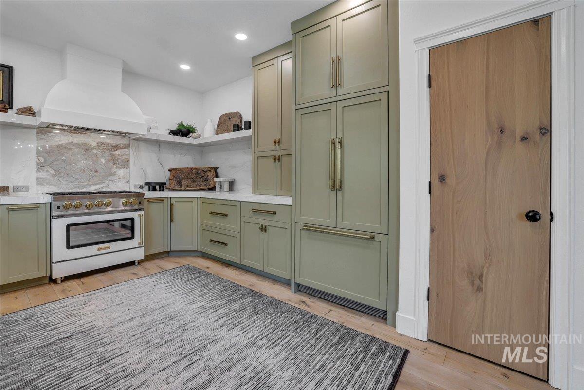 Kitchen featuring green cabinetry, open shelves, high end range, light wood-style floors, and custom exhaust hood