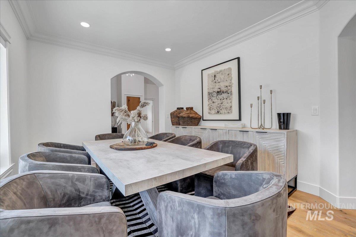 Dining area with arched walkways, crown molding, wood finished floors, and recessed lighting
