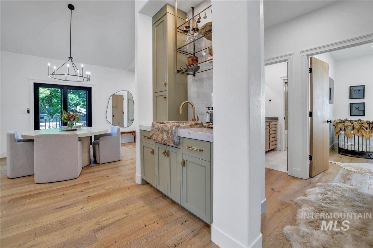 Corridor featuring light wood-style flooring, a chandelier, and vaulted ceiling