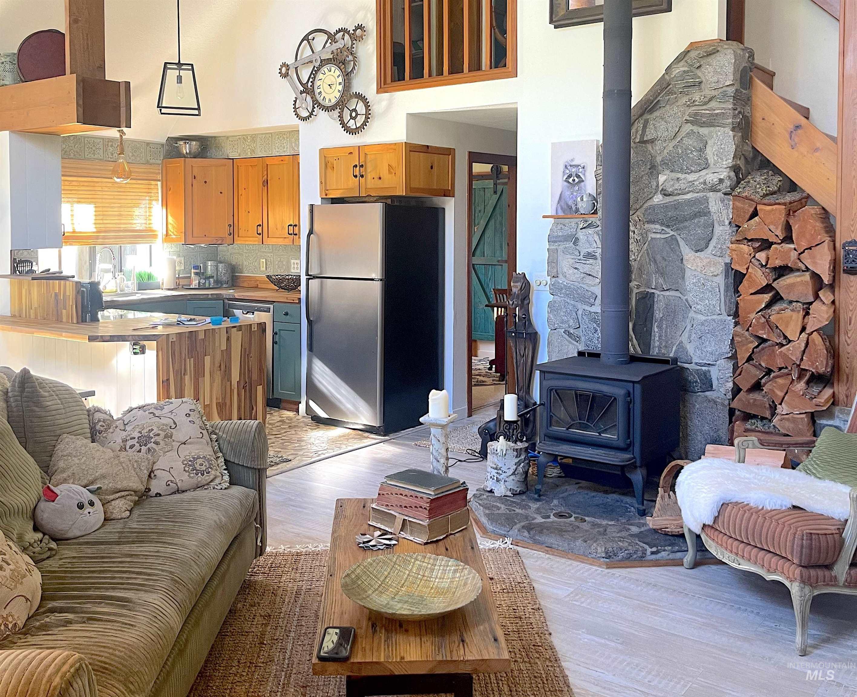 Living room with a wood stove, light wood-type flooring, and a high ceiling