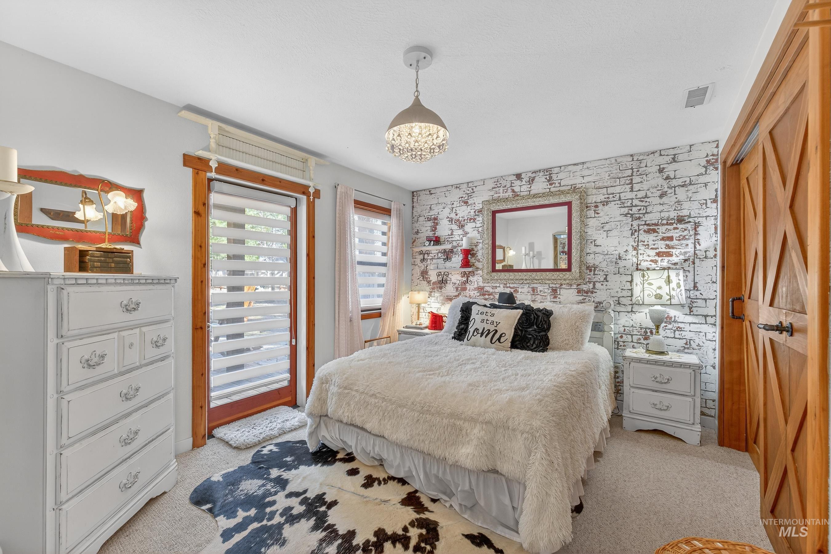 Accent brick-patterned wall with recessed shelving, chandelier-style ceiling fixture, and wood-finish barn door