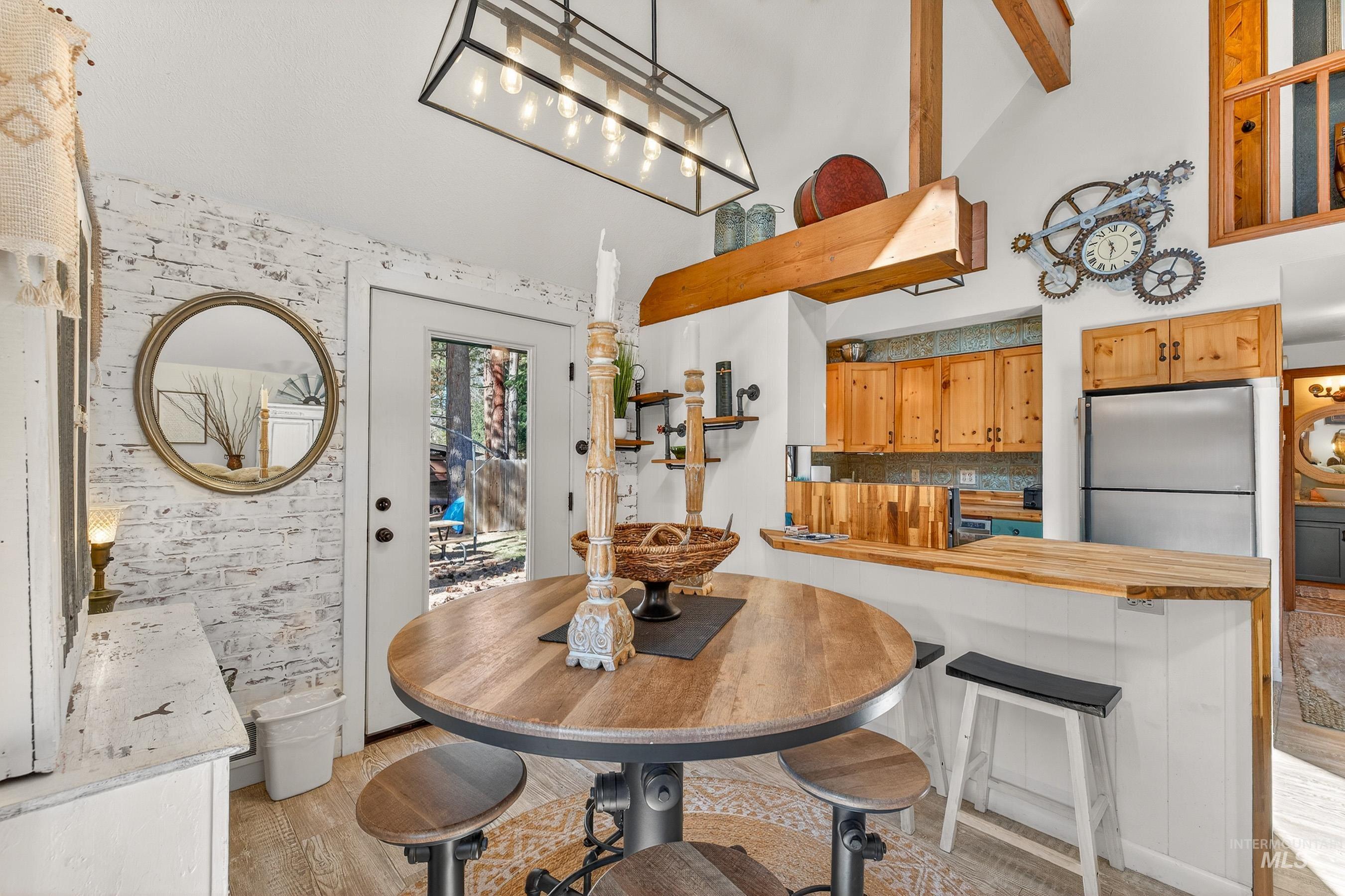 Dining area featuring a circular wood-finish table, wood-finish flooring, and a white-washed brick accent wall