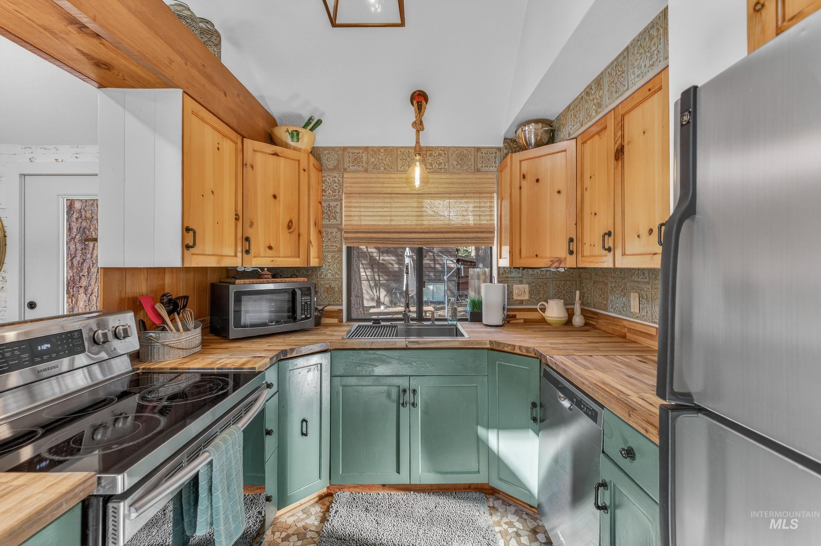 Kitchen featuring wood-finish countertops, natural wood upper cabinetry, and teal lower cabinetry