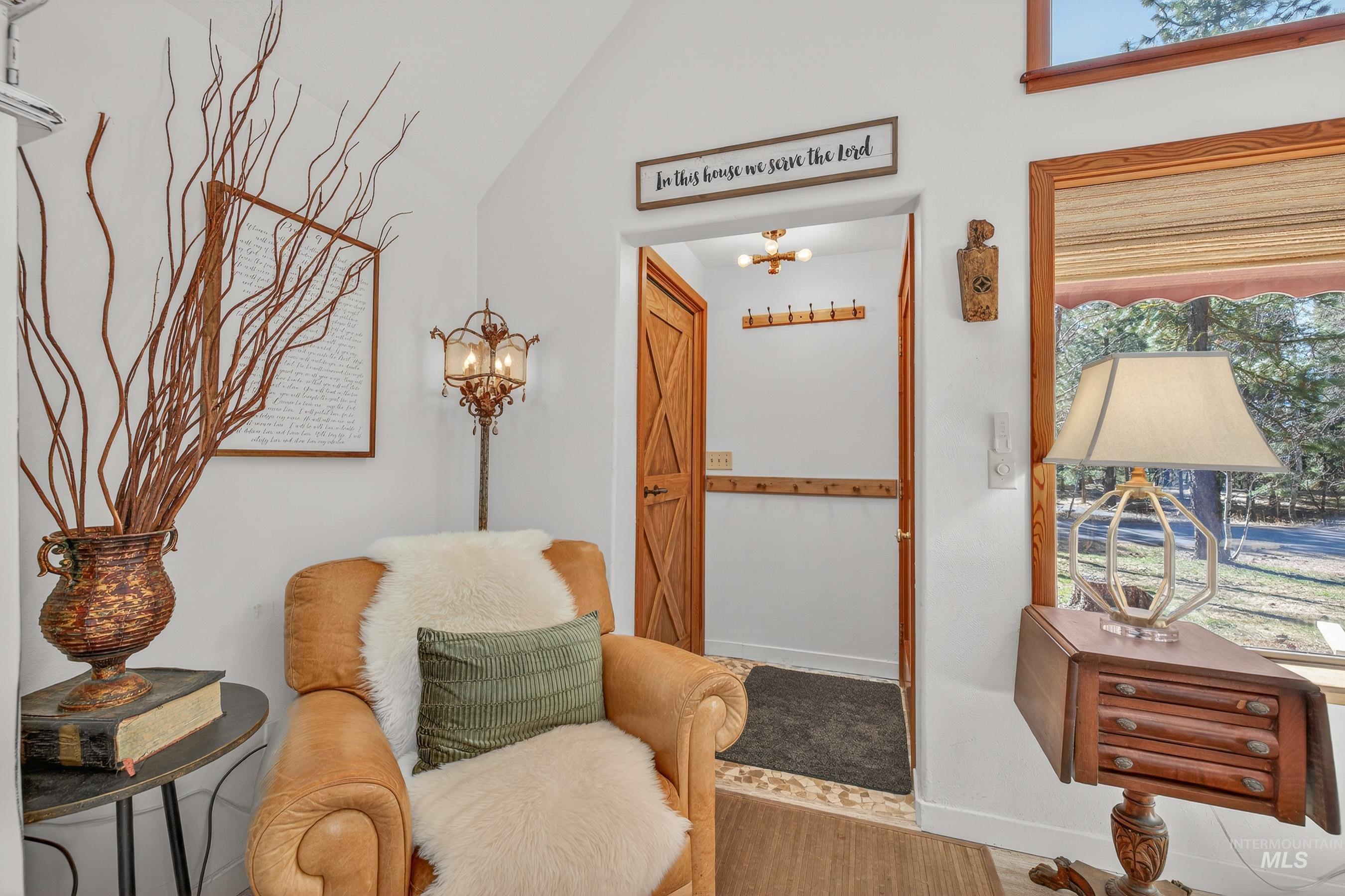 Vaulted white ceilings featuring a wood-trimmed window, wood-finish flooring, and a wood-paneled door