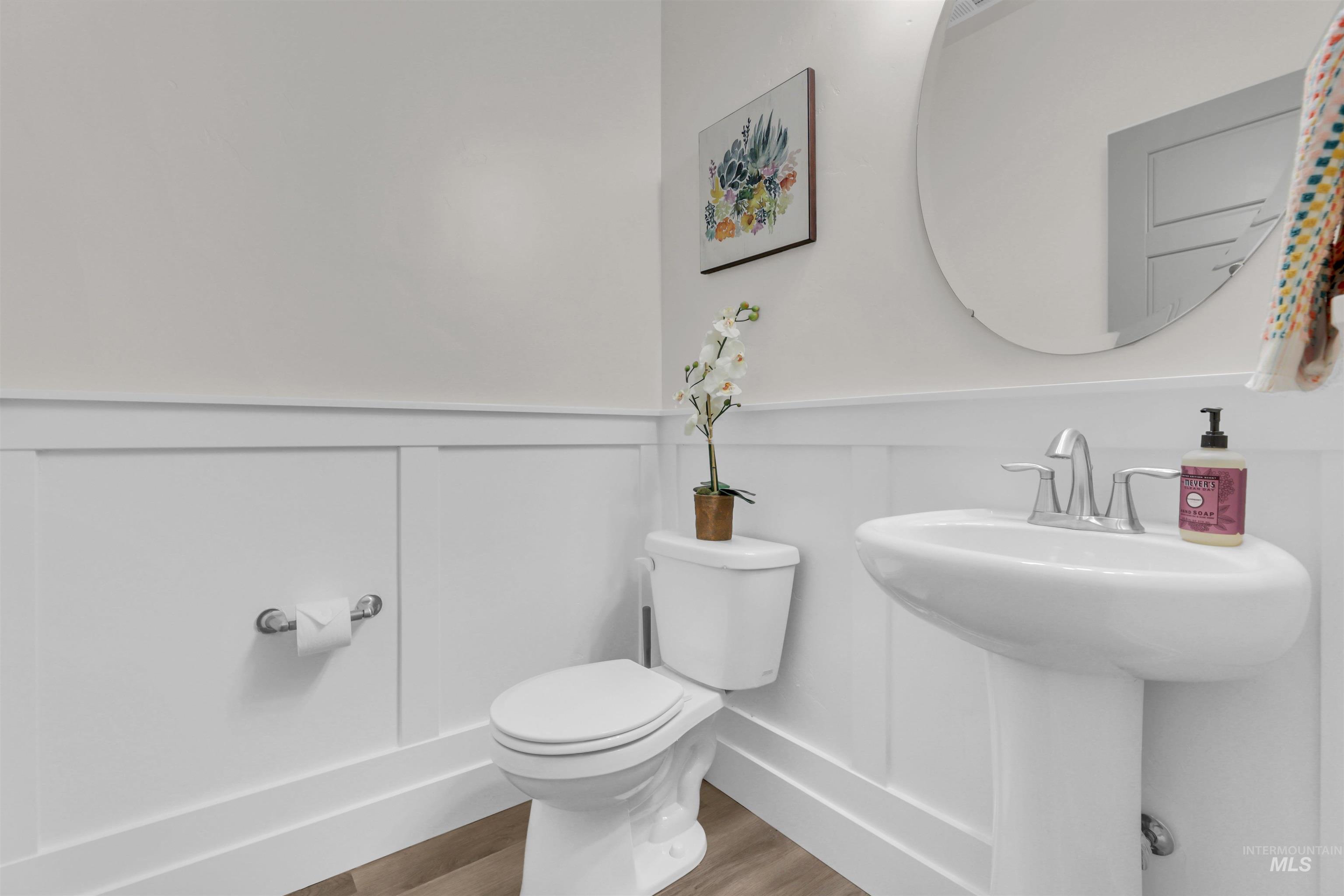 Bathroom with a wainscoted wall, wood finished floors, and a decorative wall