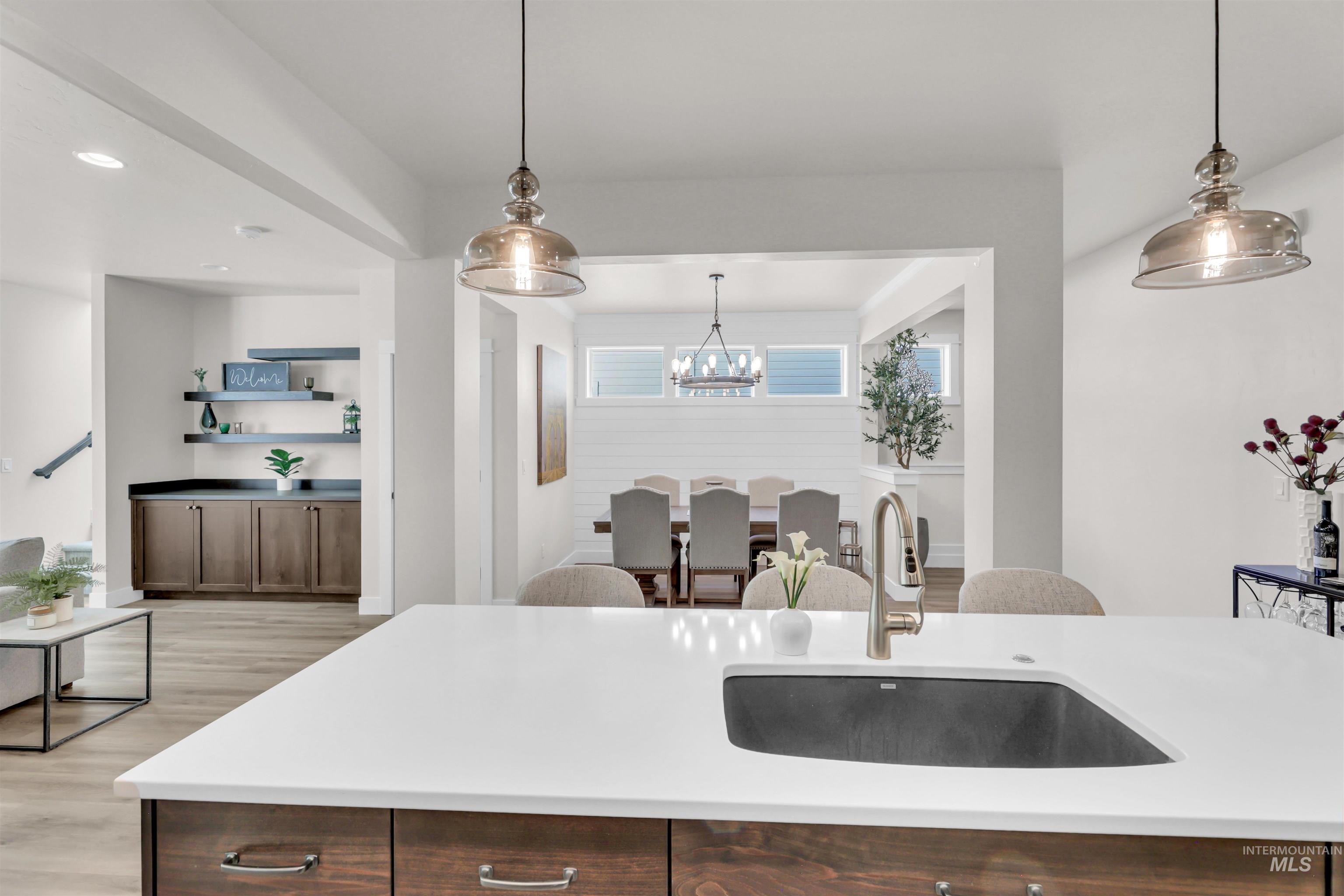 Kitchen with light wood-type flooring, recessed lighting, pendant lighting, light stone countertops, and dark brown cabinetry