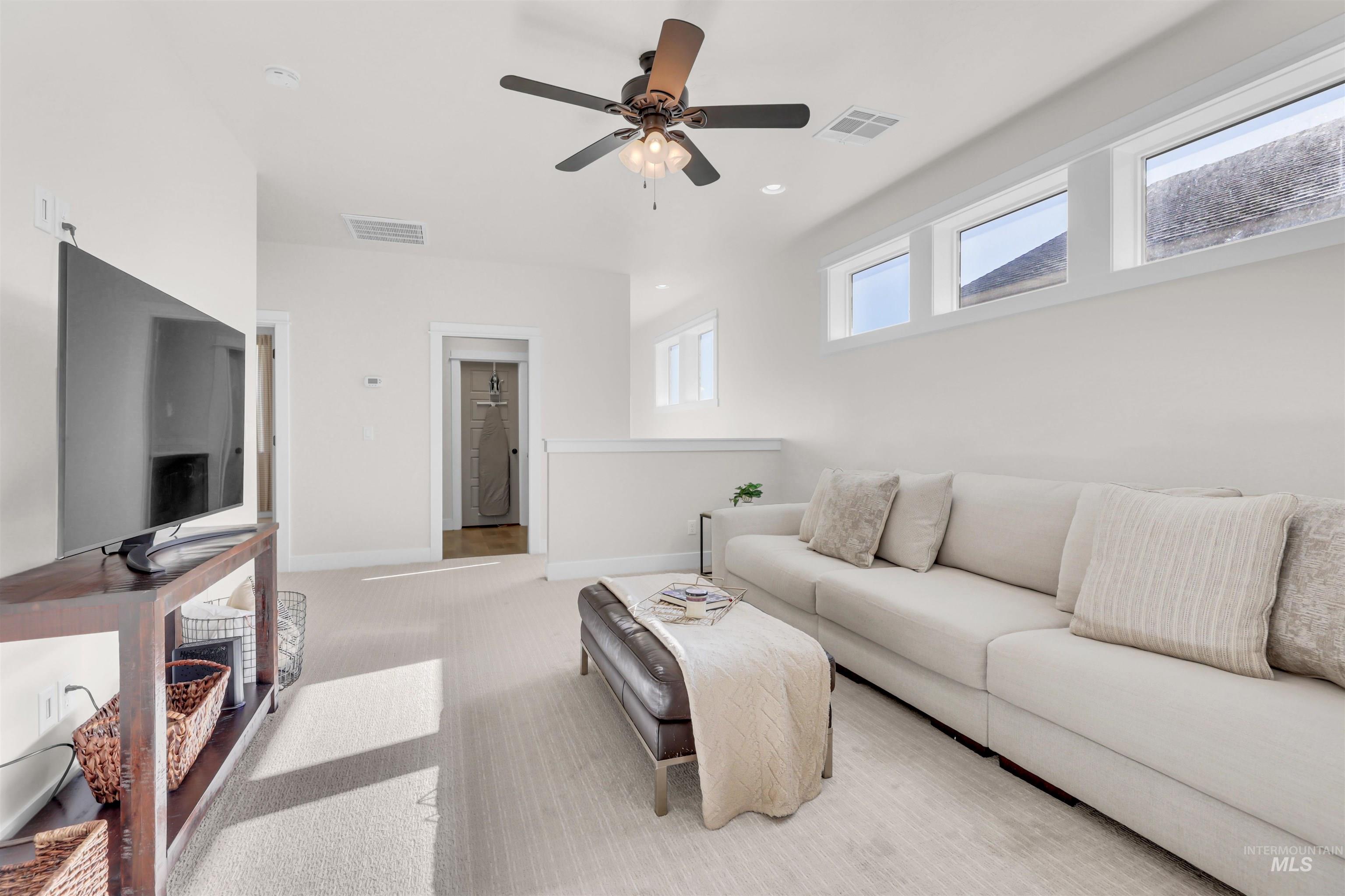 Living area featuring light carpet, ceiling fan, and recessed lighting