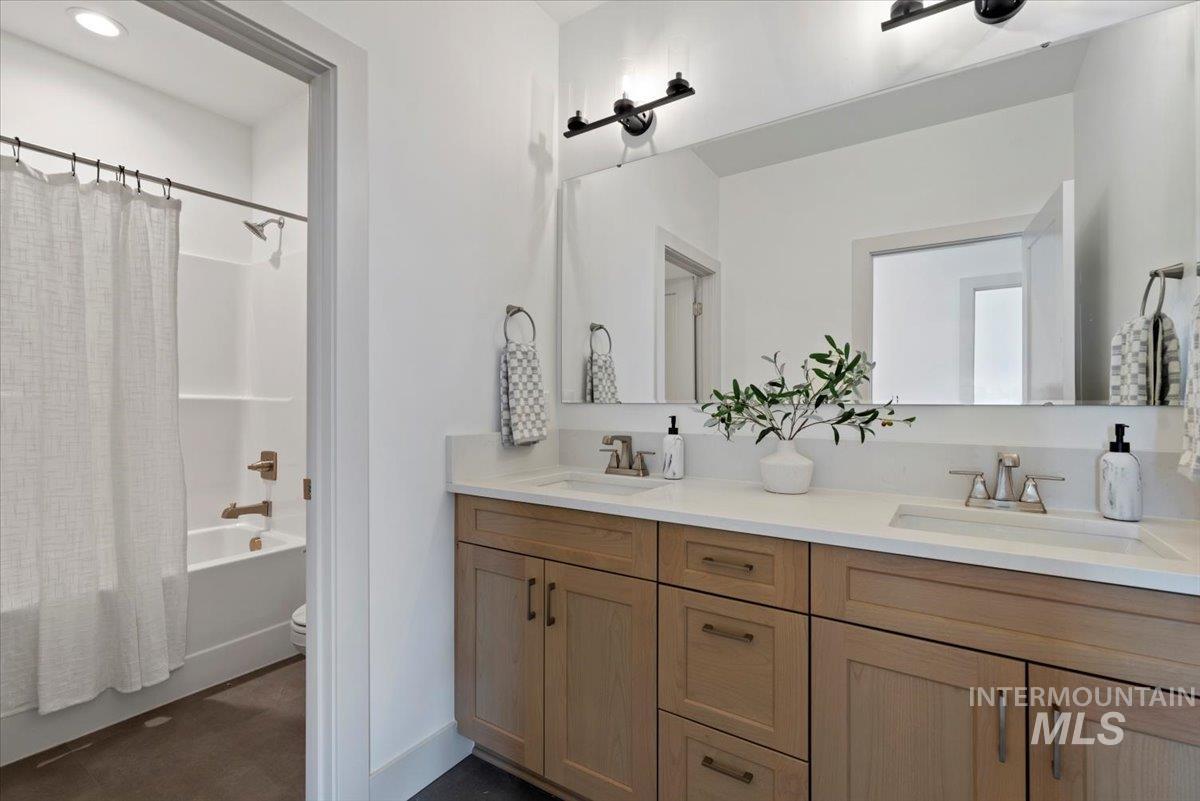 Bathroom featuring double vanity and shower / bath combination with curtain