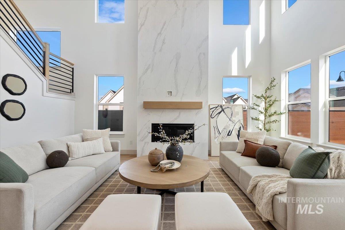 Living area with a high ceiling, a high end fireplace, wood finished floors, and plenty of natural light