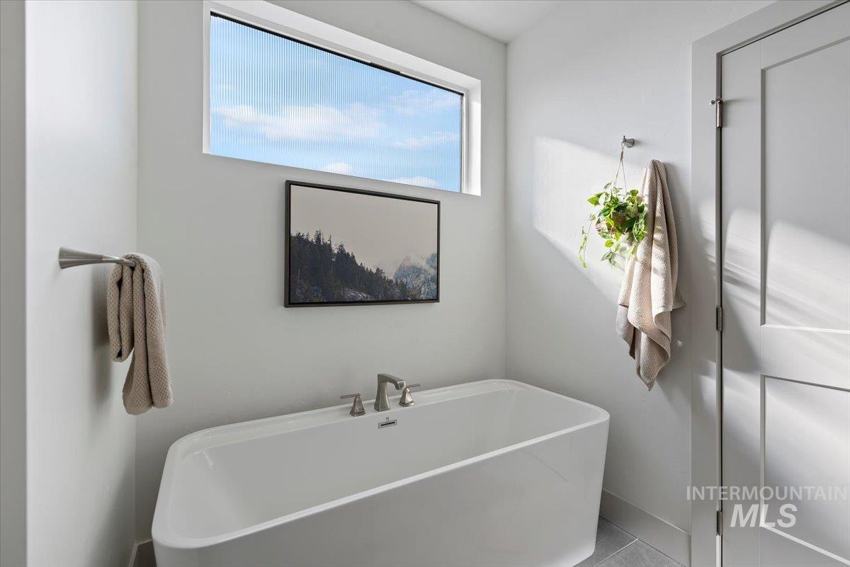 Bathroom featuring a soaking tub and baseboards