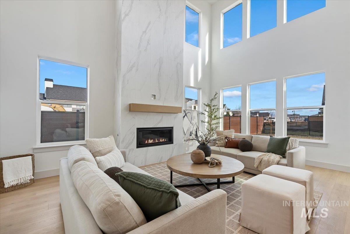 Living room with light wood-style floors, a high ceiling, and a high end fireplace