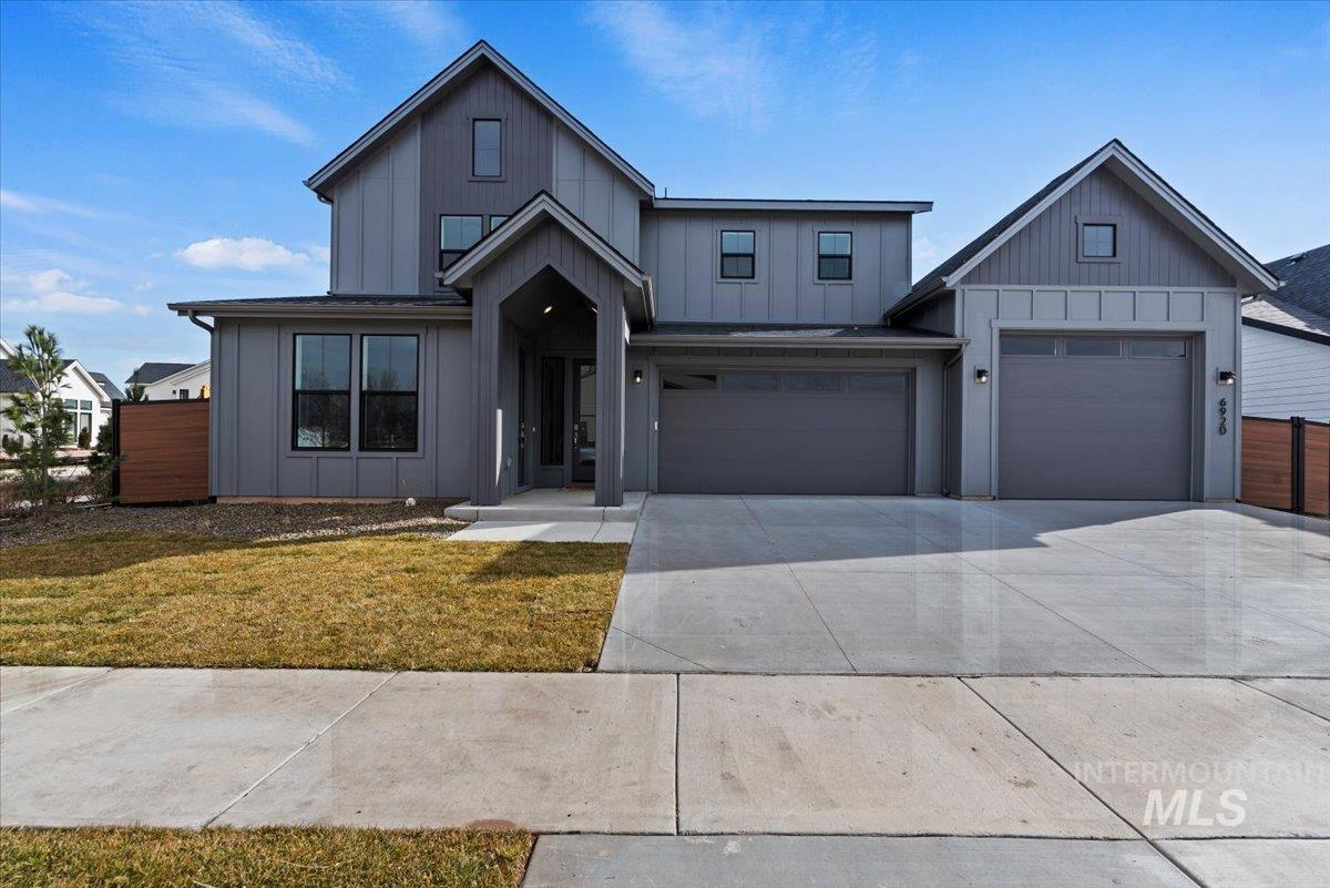 Modern farmhouse style home with board and batten siding, a front lawn, concrete driveway, and a garage